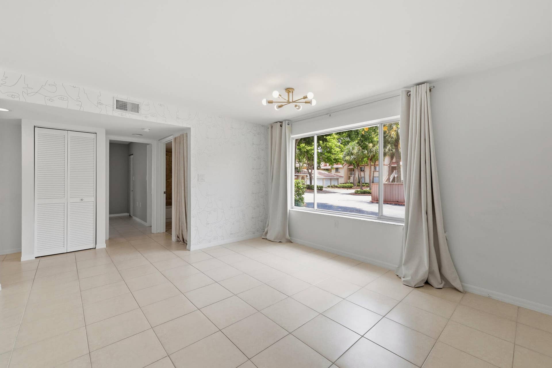 20101 Glenmoor Drive, West Palm Beach, West Palm Beach, FL 33409 Bright living space featuring large format tile flooring, a modern sputnik light fixture, and a wide window with exterior landscaping