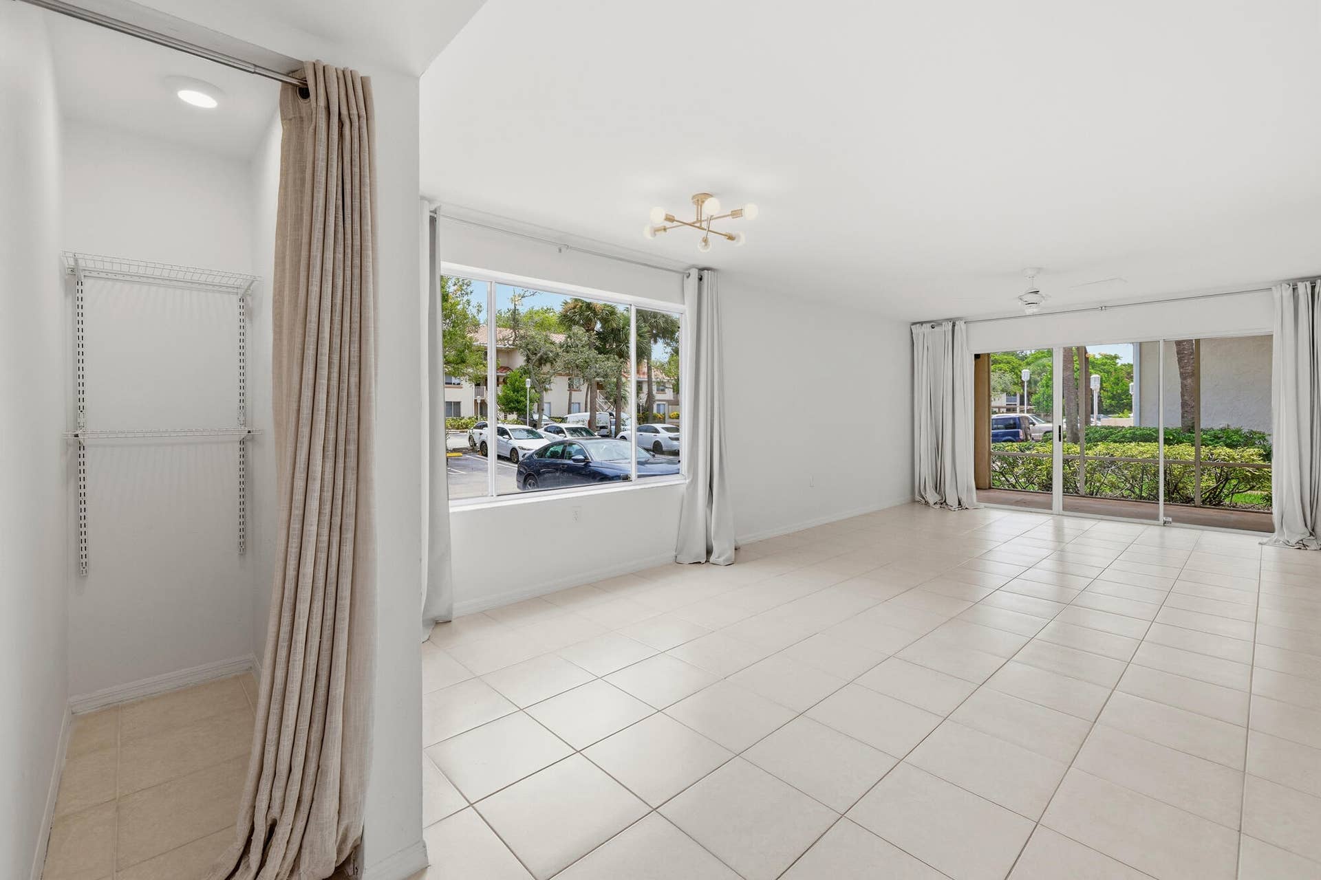 20101 Glenmoor Drive, West Palm Beach, West Palm Beach, FL 33409 Spacious room featuring neutral tile flooring, a modern sputnik-style ceiling fixture, and a large window providing ample natural light