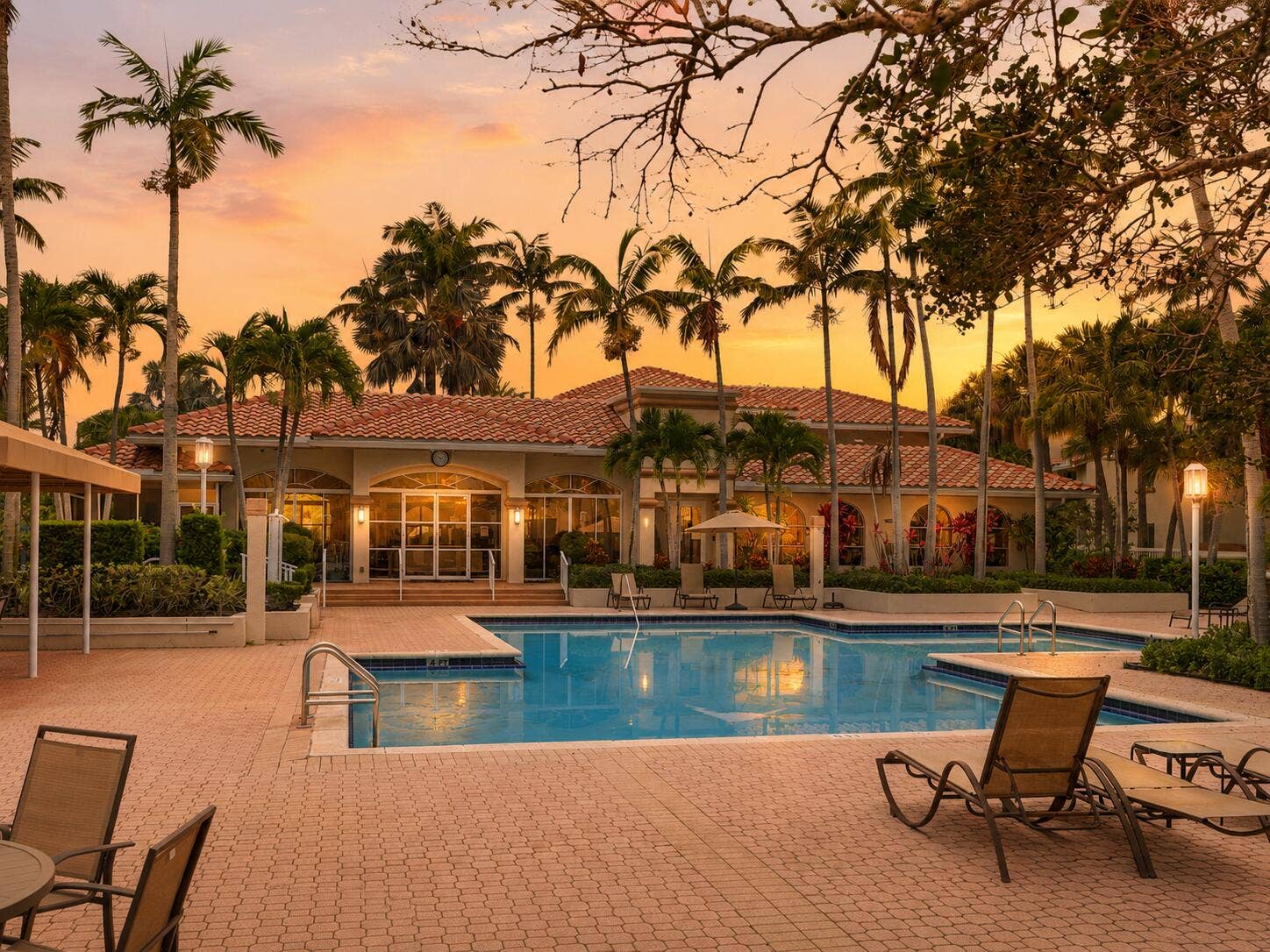 20101 Glenmoor Drive, West Palm Beach, West Palm Beach, FL 33409 Resort-style South Florida pool at sunset with palm trees, lounge chairs, and a warm golden sky.