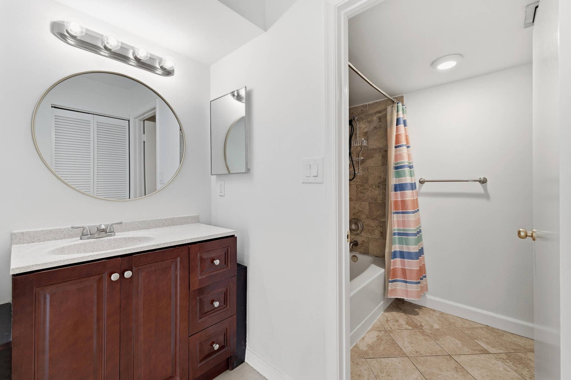 20101 Glenmoor Drive, West Palm Beach, West Palm Beach, FL 33409 Bathroom featuring a dark wood-finish vanity with a light countertop, an oval mirror, and a four-bulb vanity light fixture