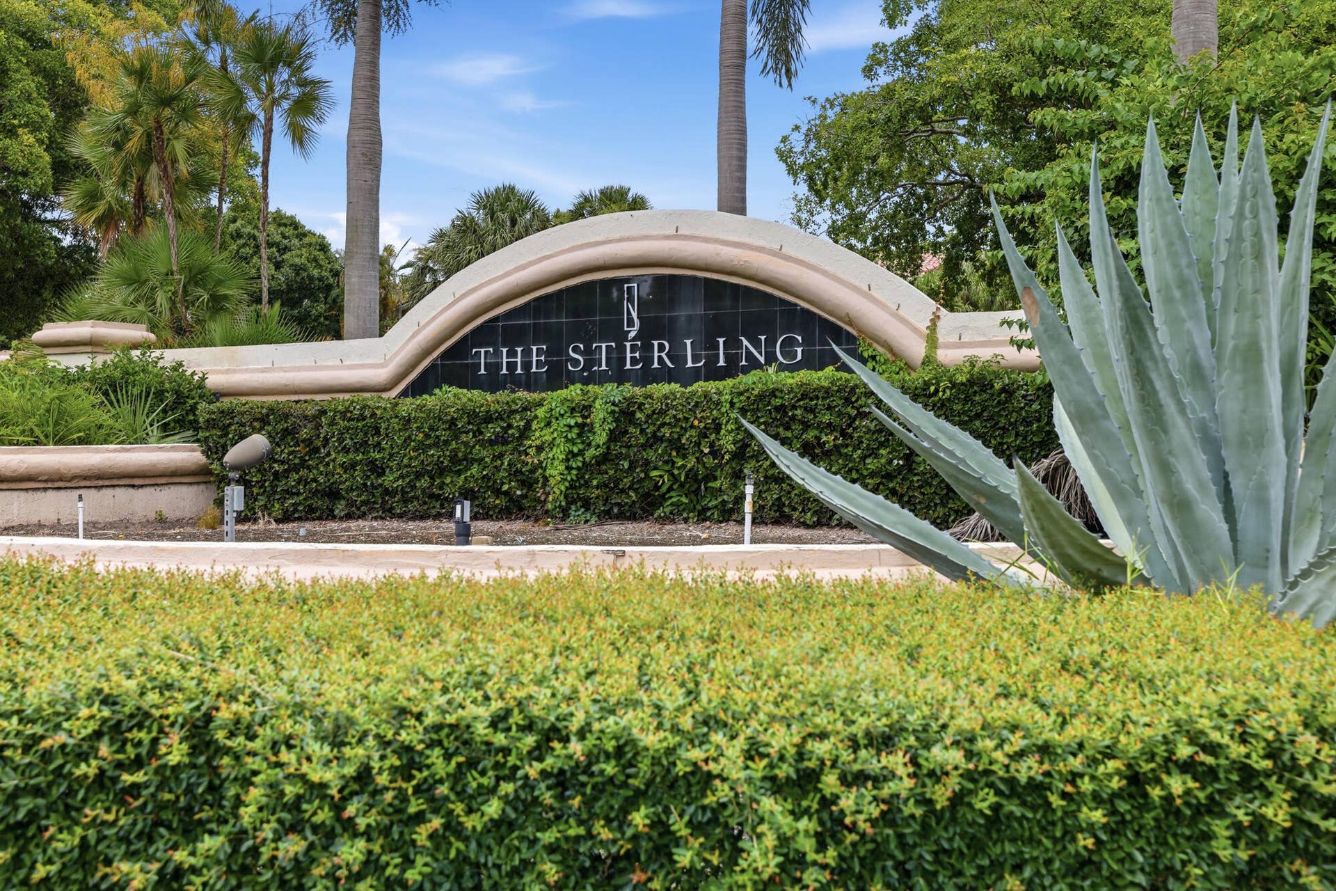 20101 Glenmoor Drive, West Palm Beach, West Palm Beach, FL 33409 Curved stone entryway sign featuring "THE STERLING" lettering, dark stone backdrop, and integrated landscaping