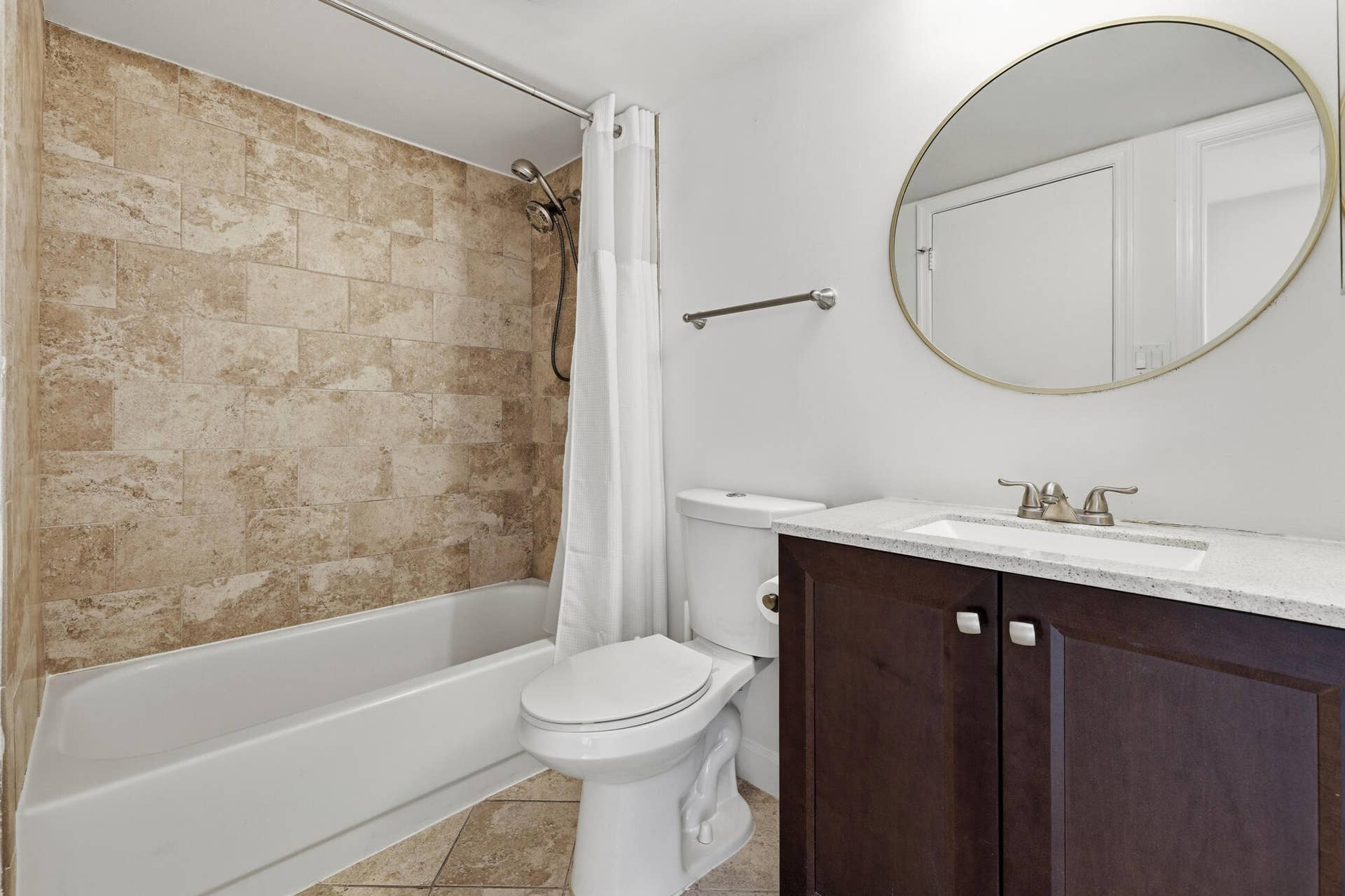 20101 Glenmoor Drive, West Palm Beach, West Palm Beach, FL 33409 Bathroom featuring a tub/shower combination with tile surround, a dark wood-finish vanity with a light countertop, an undermount sink, and a circular wall mirror