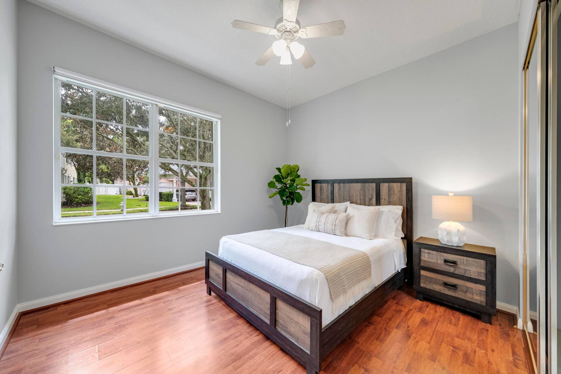 254 Marlberry Circle, Jupiter, FL 33458 Bedroom with hardwood floors and a picture window framing the oak-lined street
