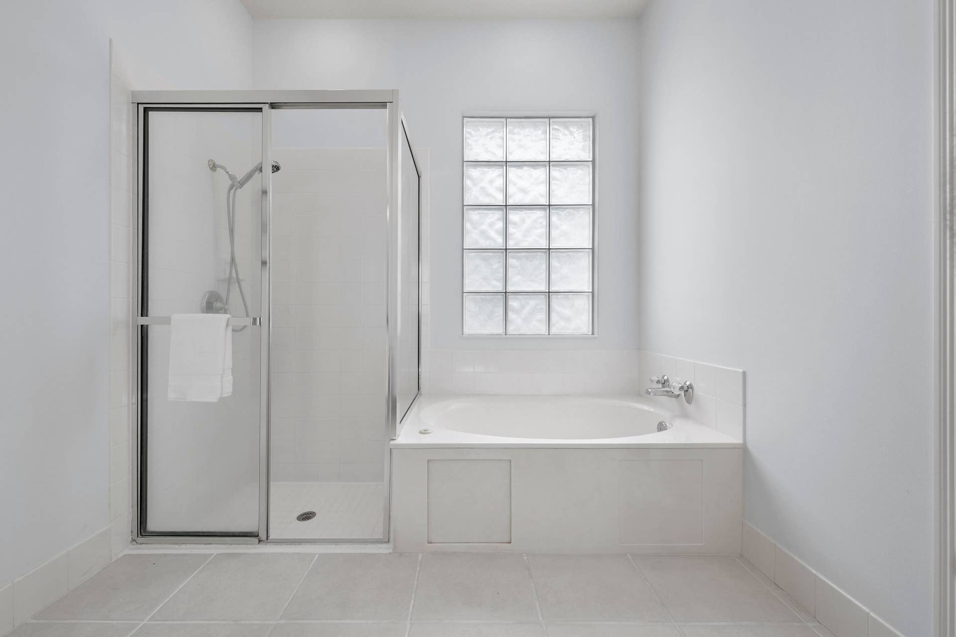 254 Marlberry Circle, Jupiter, FL 33458 Primary bathroom with walk-in shower and soaking tub beneath a glass block window