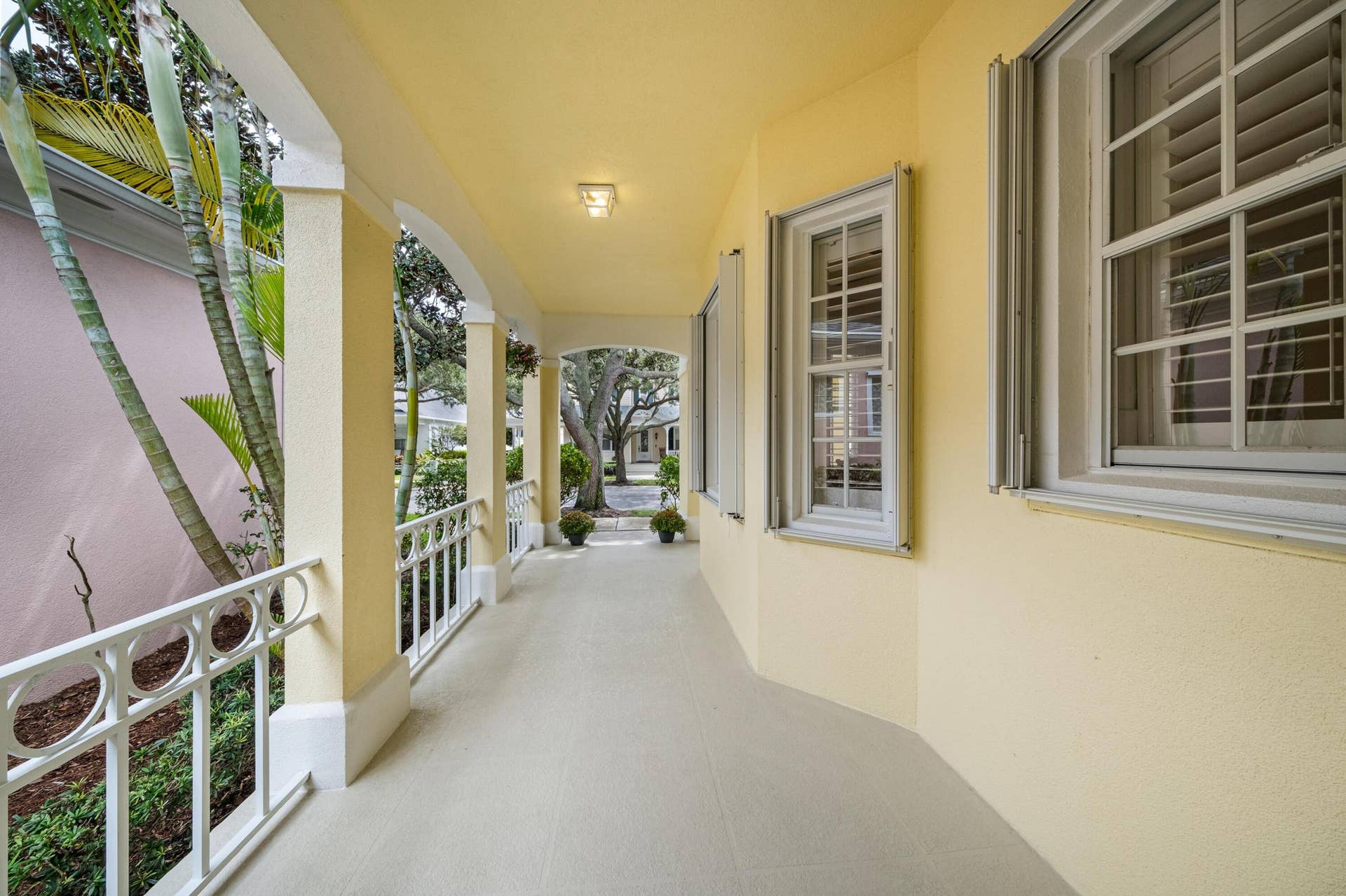 254 Marlberry Circle, Jupiter, FL 33458 Covered front porch colonnade with decorative railings, framing views of the mature oaks
