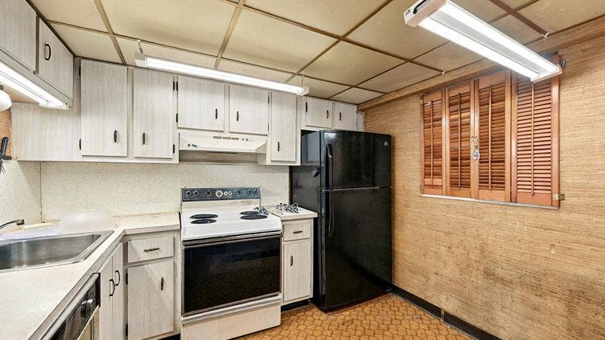 4311 CRYSTAL LAKE Drive, #110, Deerfield Beach, FL 33064 Kitchen featuring white cabinetry with dark hardware, a stainless steel sink, a white electric range, and a black refrigerator