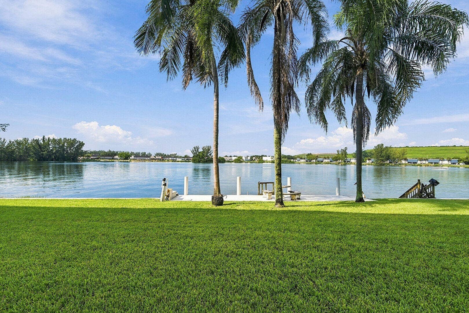 4311 CRYSTAL LAKE Drive, #110, Deerfield Beach, FL 33064 Manicured lawn with mature palm trees, private dock structure, and waterfront access