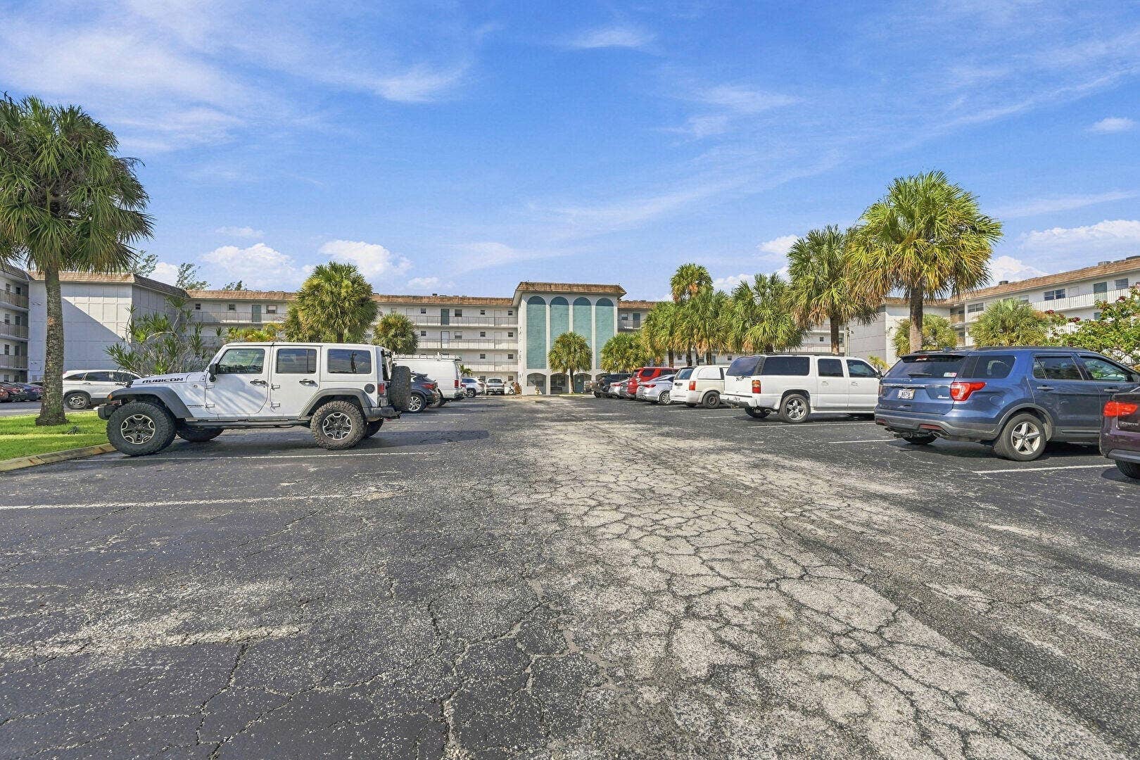 4311 CRYSTAL LAKE Drive, #110, Deerfield Beach, FL 33064 Multi-story building exterior with multiple windows, framed by mature palm trees