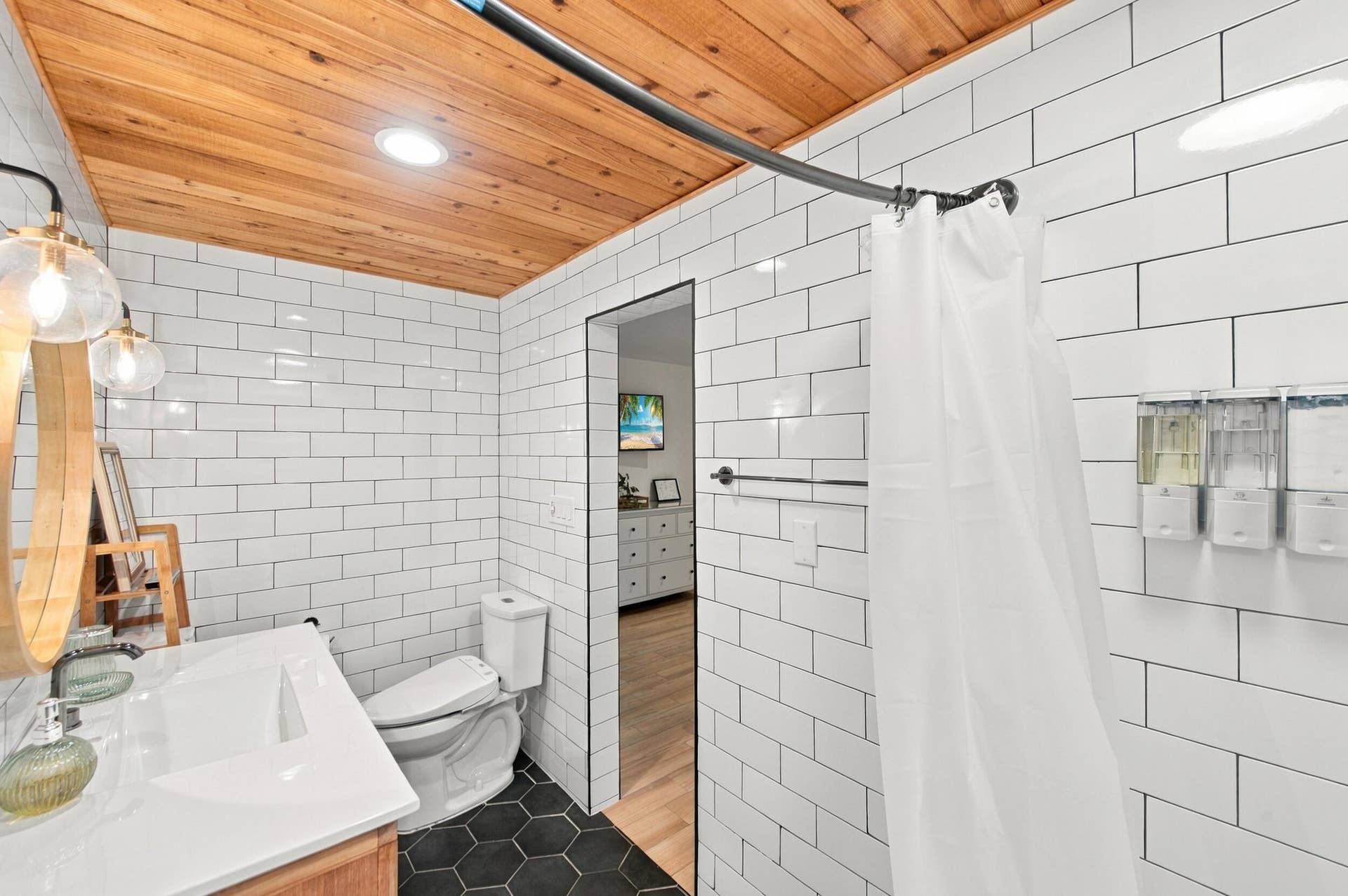 2496 BIMINI Lane, Fort Lauderdale, FL 33312 White subway tile walls, wood-finish ceiling, black hexagonal floor tiles, white vanity with integrated sink, and clear glass globe light fixtures