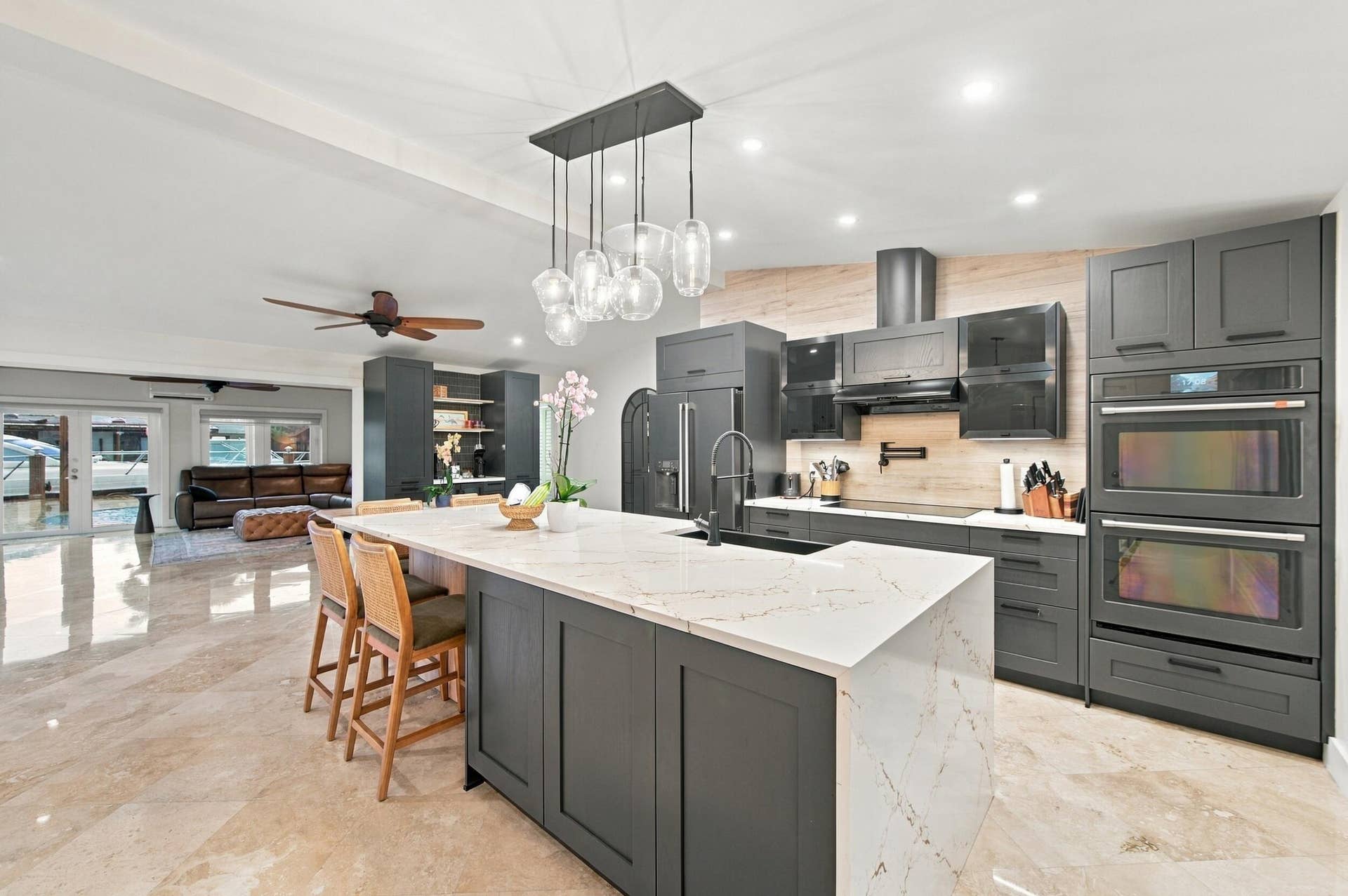2496 BIMINI Lane, Fort Lauderdale, FL 33312 Kitchen featuring a waterfall-edge island with seating, a pendant light fixture, dark cabinetry, and dual built-in ovens
