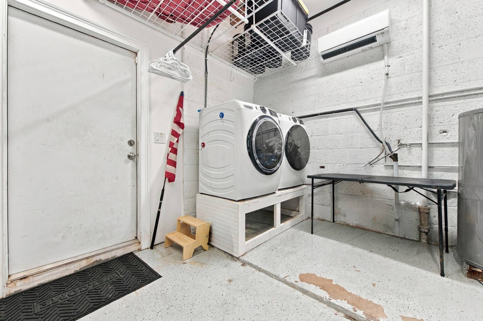 2496 BIMINI Lane, Fort Lauderdale, FL 33312 White front-loading washer and dryer, exposed concrete block walls, and overhead shelving