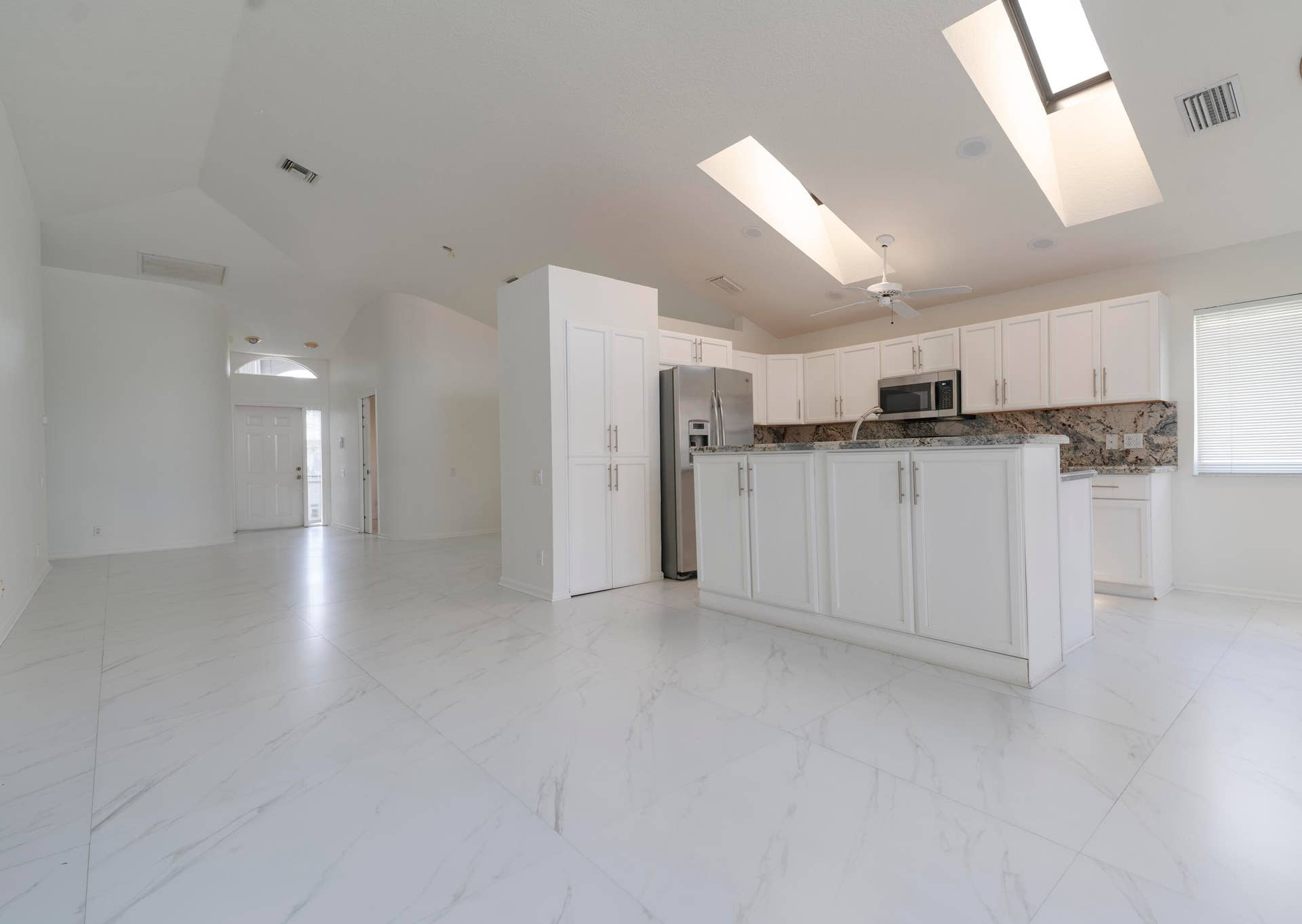 6162 BAY ISLES Drive, Boynton Beach, FL 33437 Open-concept living area featuring white large-format tile flooring and vaulted ceilings