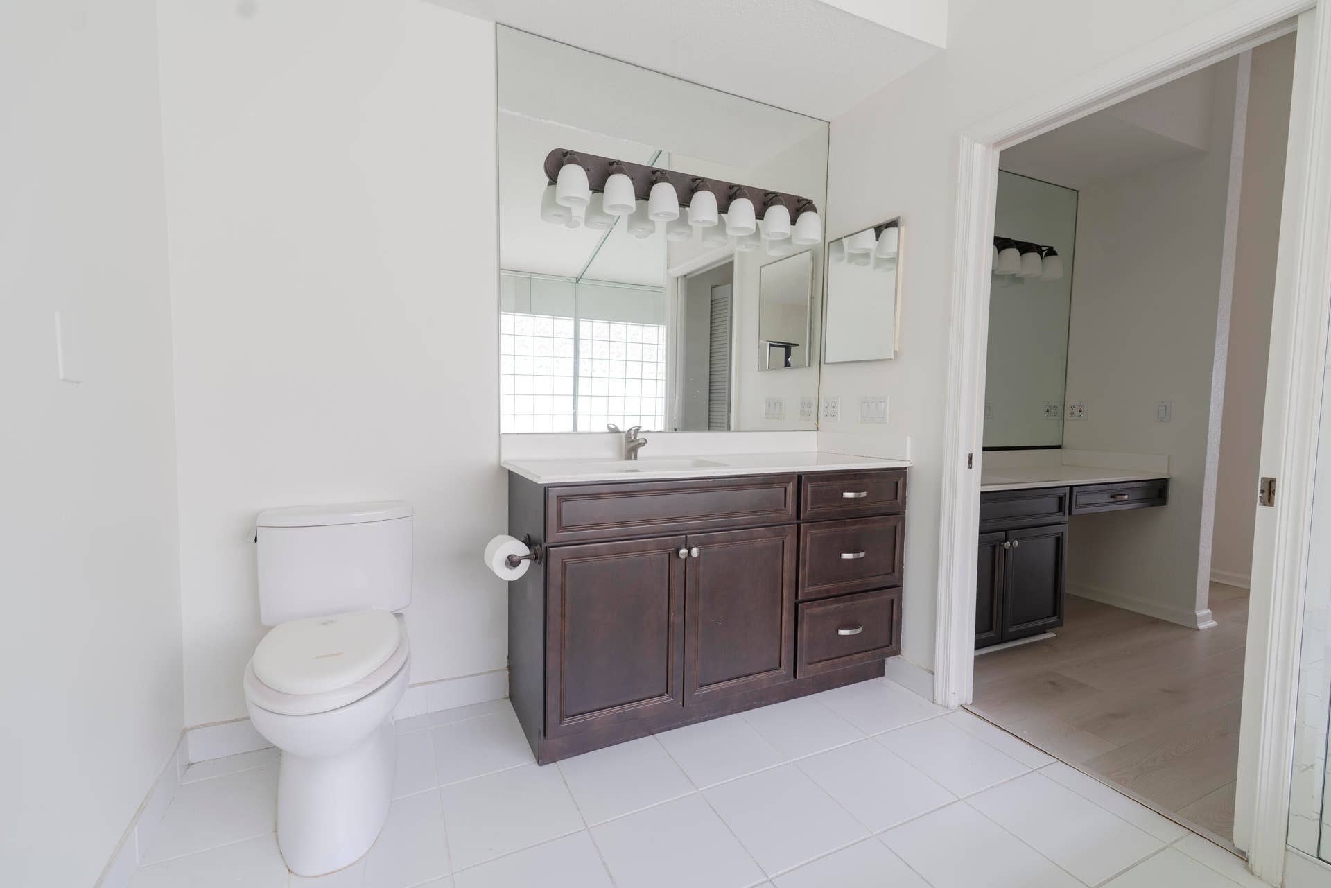 6162 BAY ISLES Drive, Boynton Beach, FL 33437 White tile flooring, extensive mirror, dark wood-finish vanity, white countertop, and glass block window