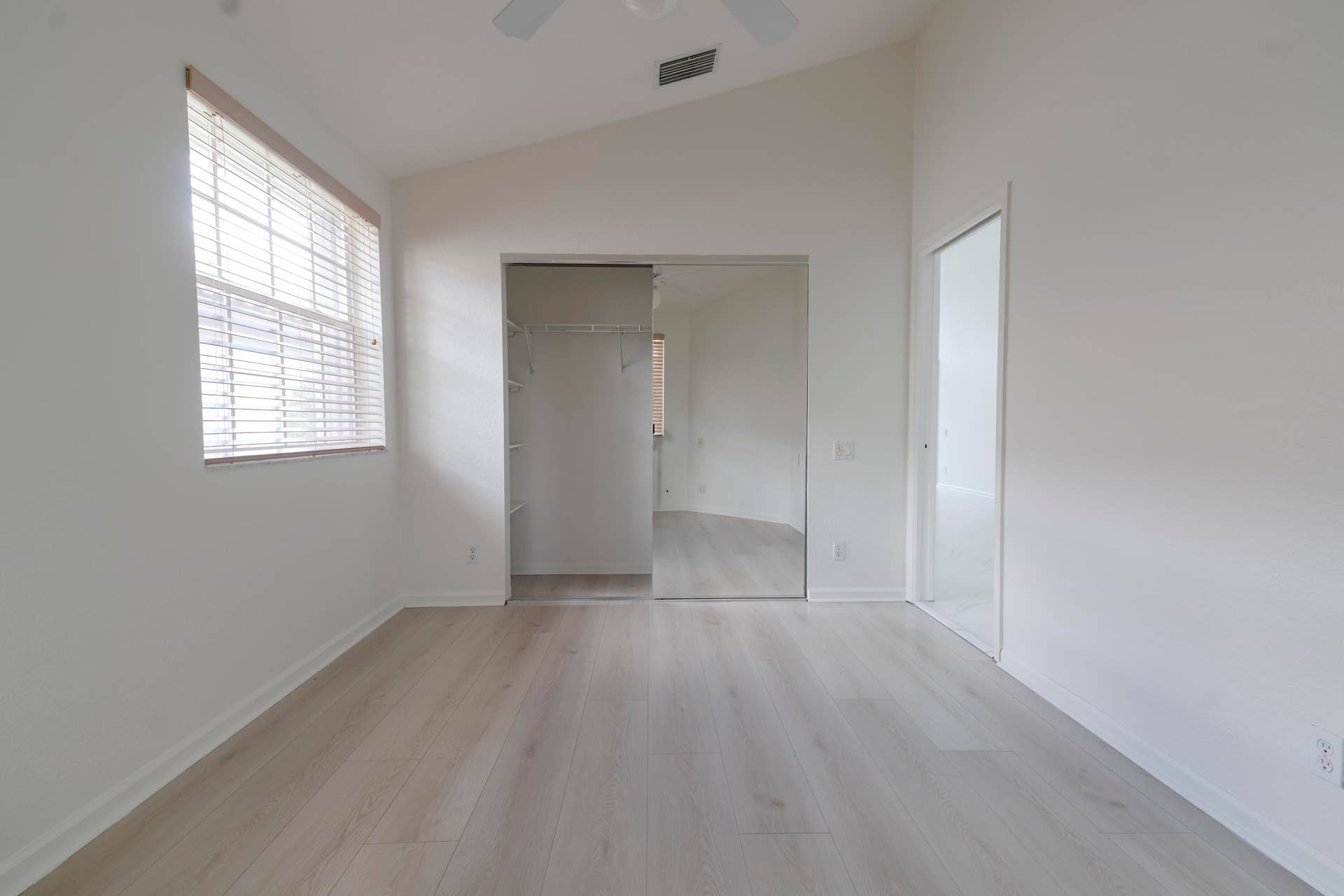 6162 BAY ISLES Drive, Boynton Beach, FL 33437 Vaulted ceiling featuring a ceiling fan, light wood-finish flooring, a window with horizontal blinds, and a mirrored closet with built-in shelving
