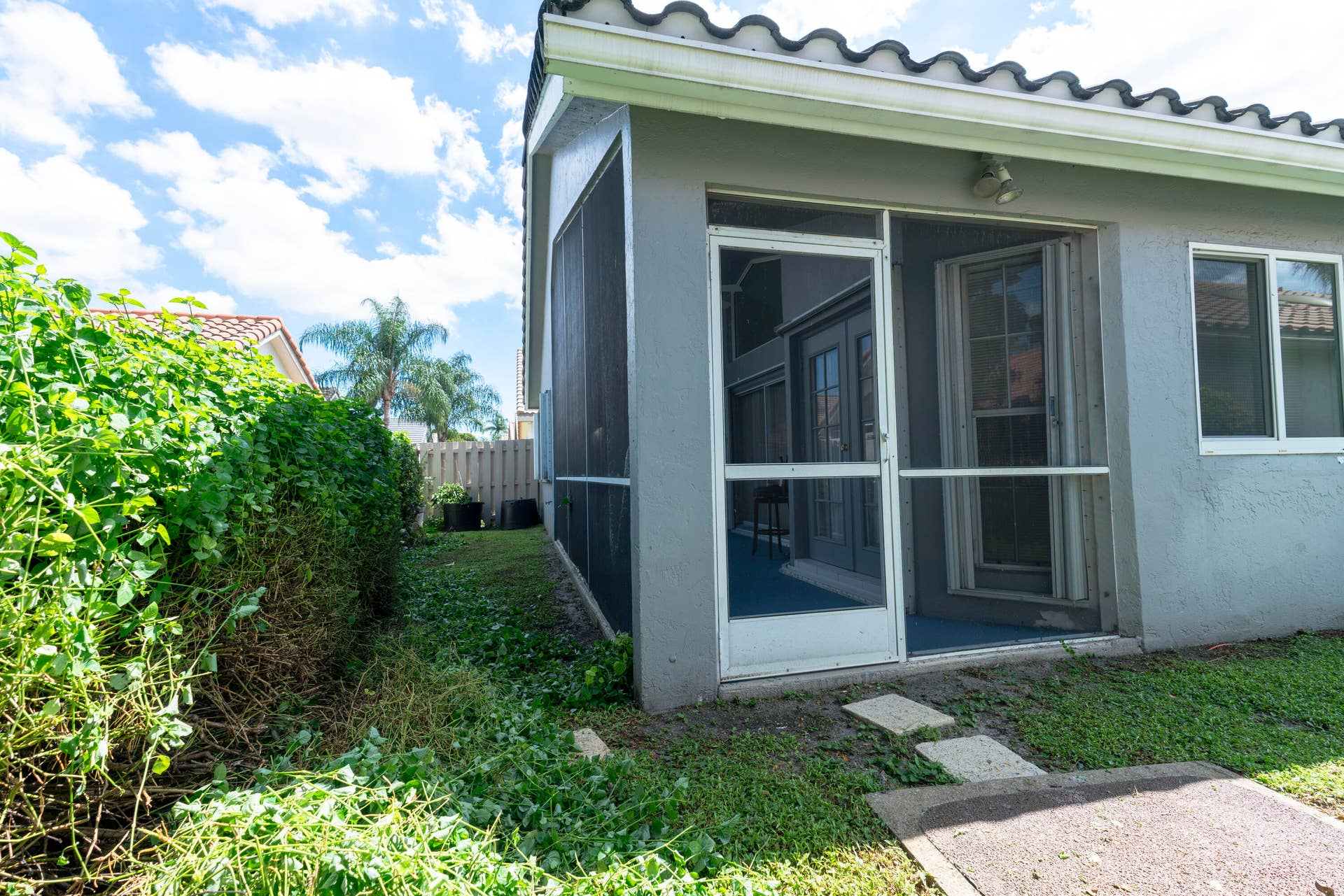 6162 BAY ISLES Drive, Boynton Beach, FL 33437 Screened patio entrance with a single-pane glass door, white window frames, and a tiled roof