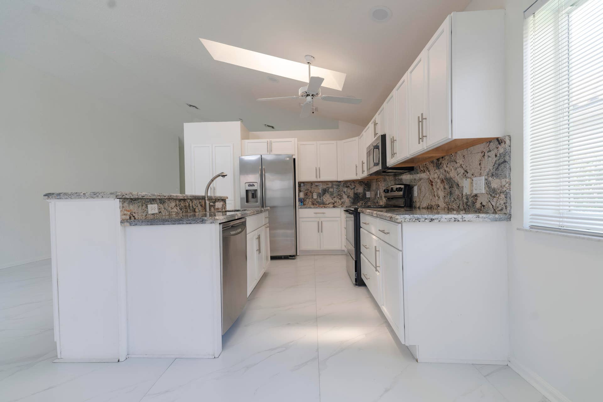 6162 BAY ISLES Drive, Boynton Beach, FL 33437 Kitchen featuring white cabinetry, light-toned countertops, stainless steel appliances, and a skylight