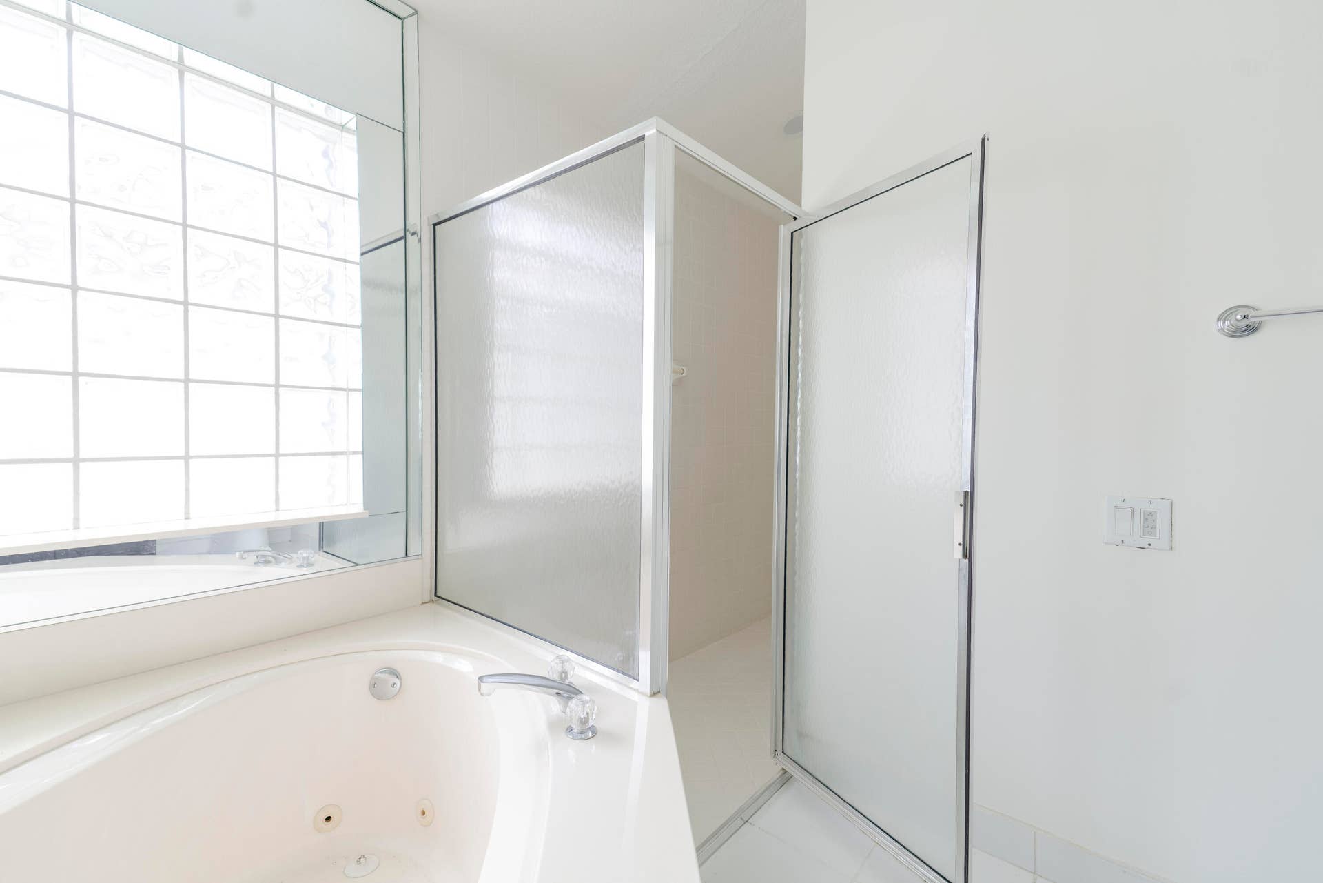 6162 BAY ISLES Drive, Boynton Beach, FL 33437 Built-in jetted tub with chrome fixtures, glass block window, and an adjacent shower enclosure with clear glass panels