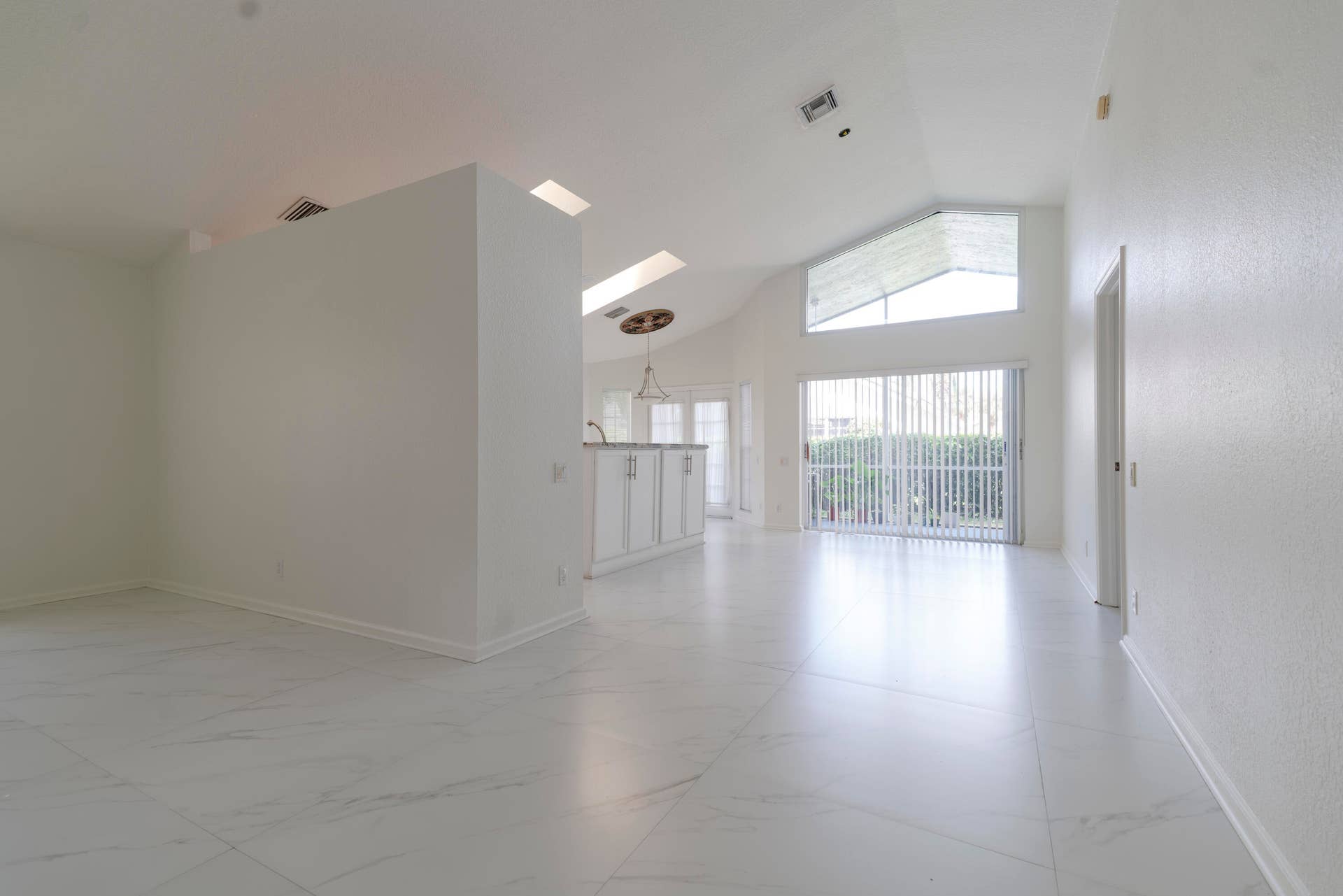 6162 BAY ISLES Drive, Boynton Beach, FL 33437 Vaulted ceilings with skylights, large format tile flooring, sliding glass doors, white cabinetry, and recessed lighting