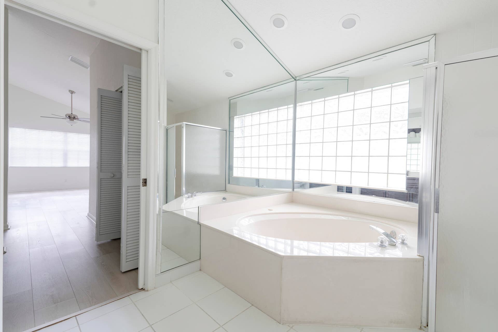 6162 BAY ISLES Drive, Boynton Beach, FL 33437 Corner soaking tub with deck-mounted fixtures, glass block window, mirrored wall, and glass-enclosed shower