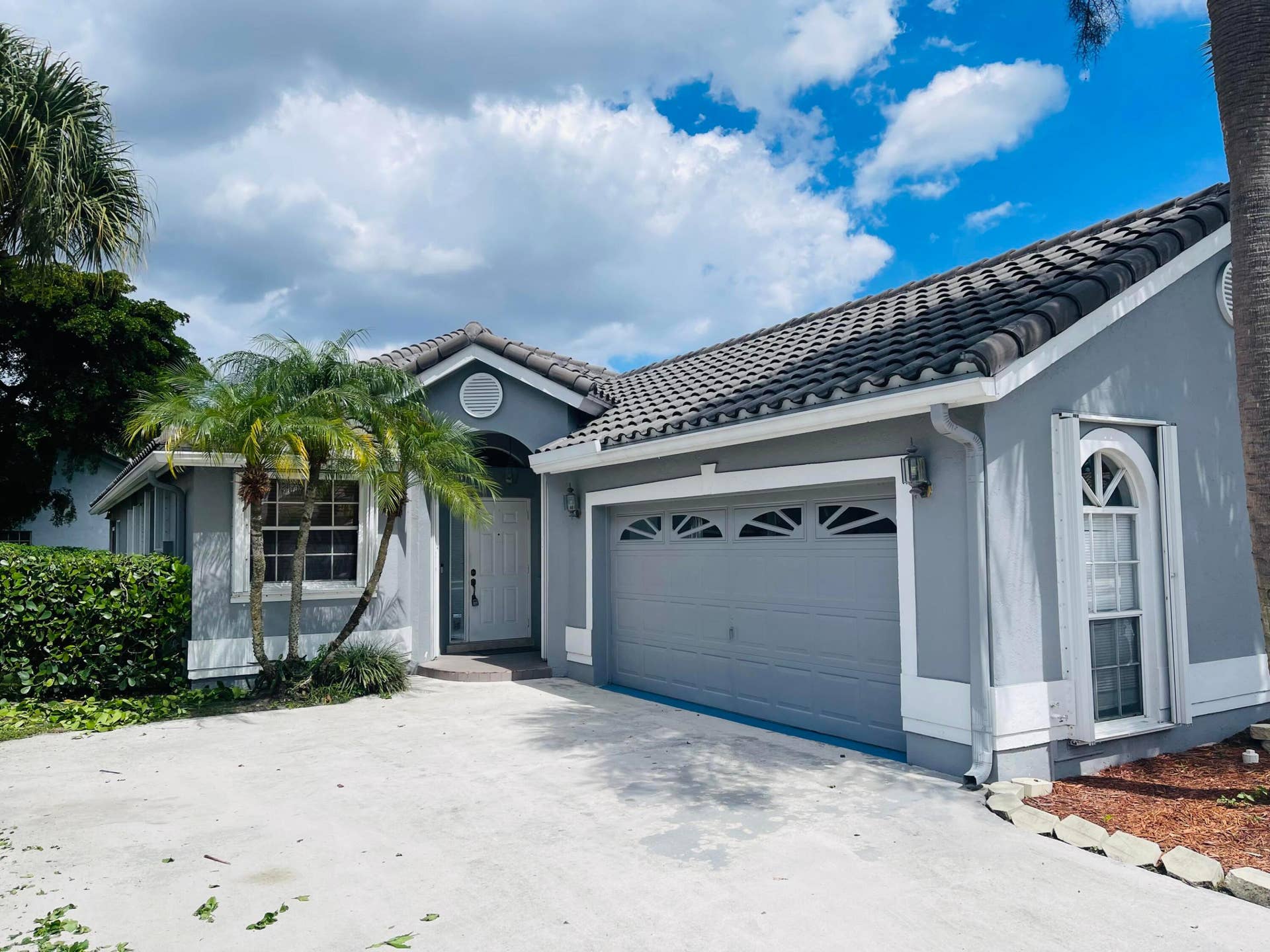 6162 BAY ISLES Drive, Boynton Beach, FL 33437 Smooth stucco exterior with a tiled roof, arched window detail, and an integrated two-car garage