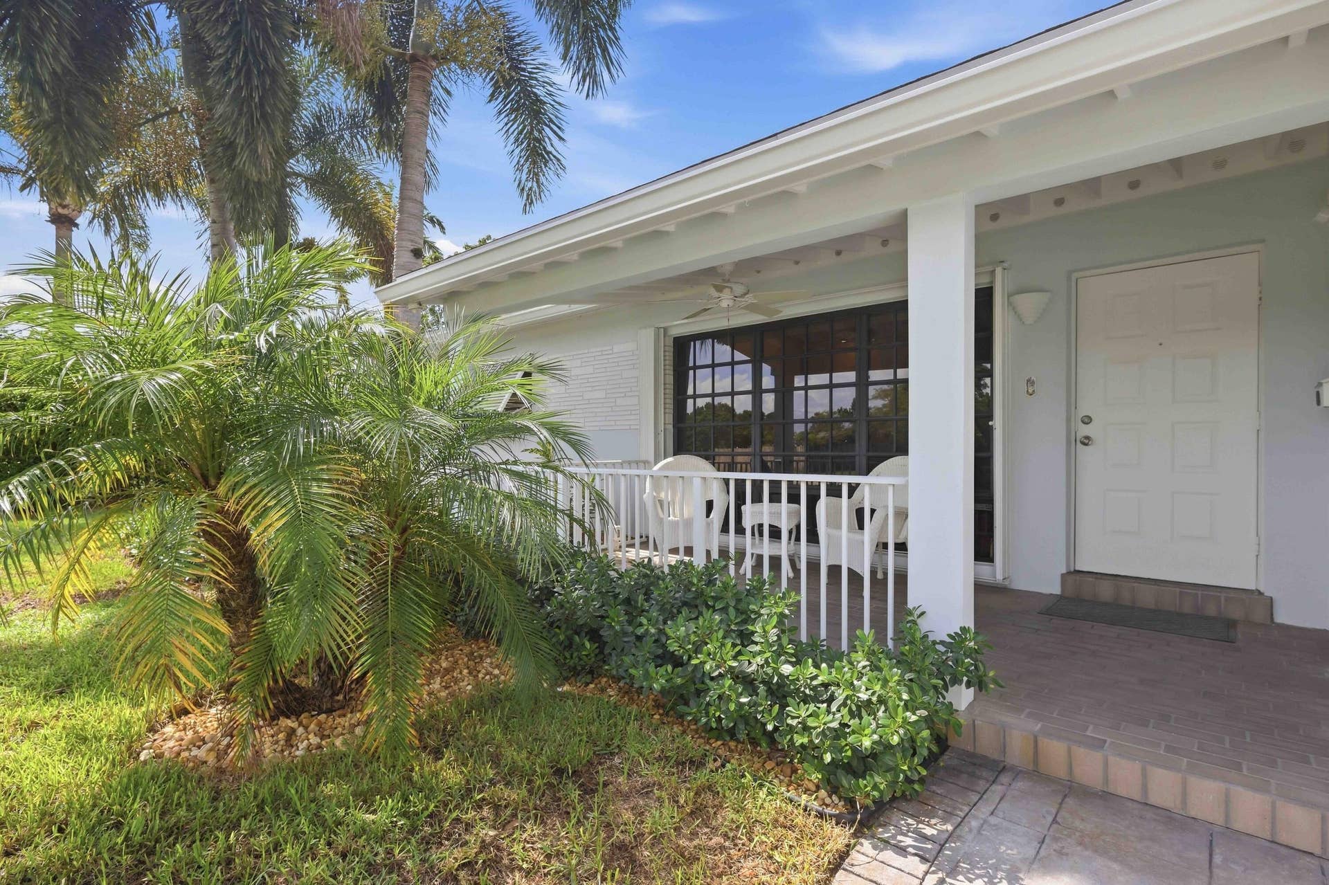 Covered front porch with white railings, screened windows, and a tiled entry