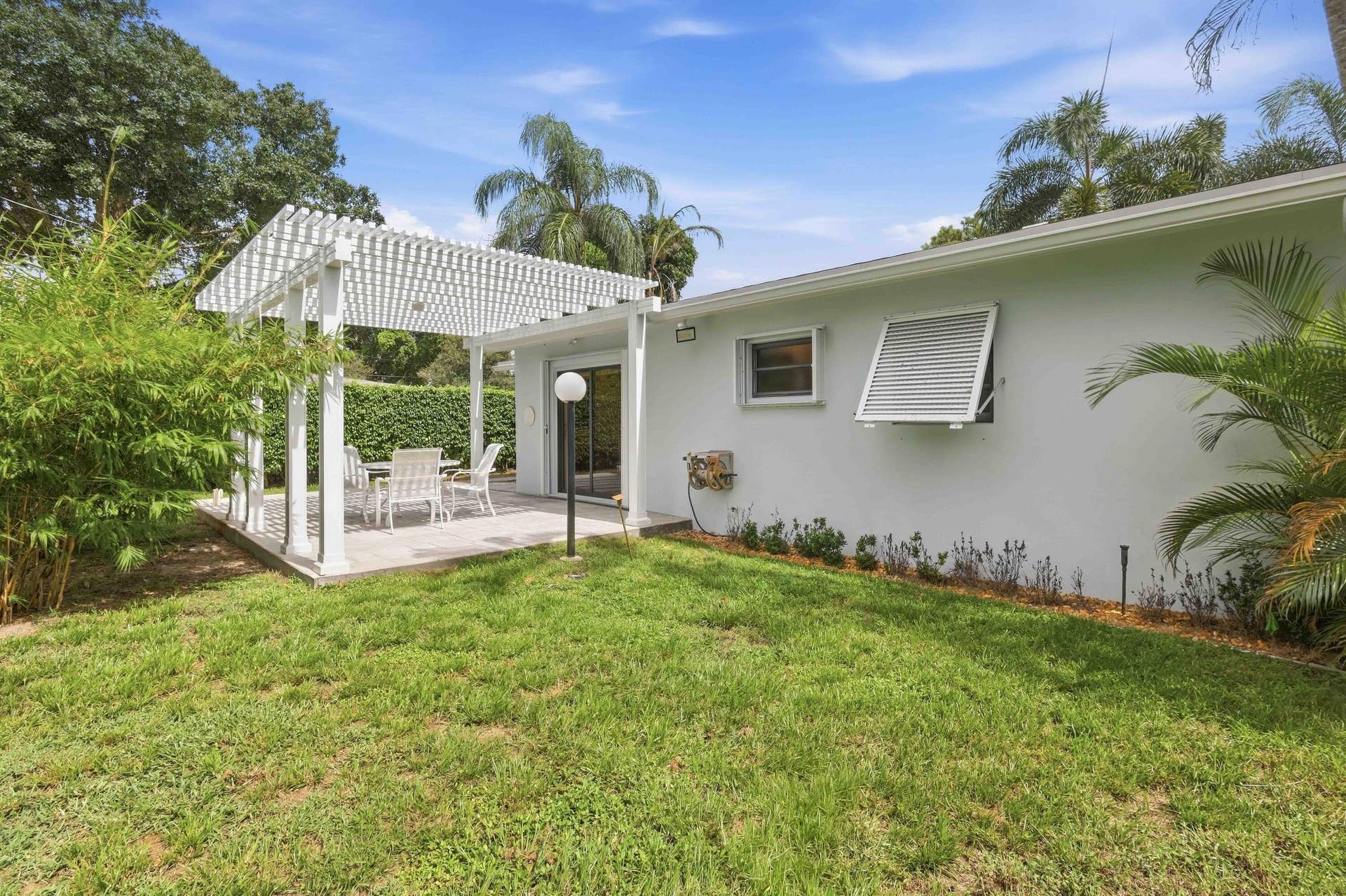 Expansive outdoor patio with a white pergola structure and a sliding glass door entry