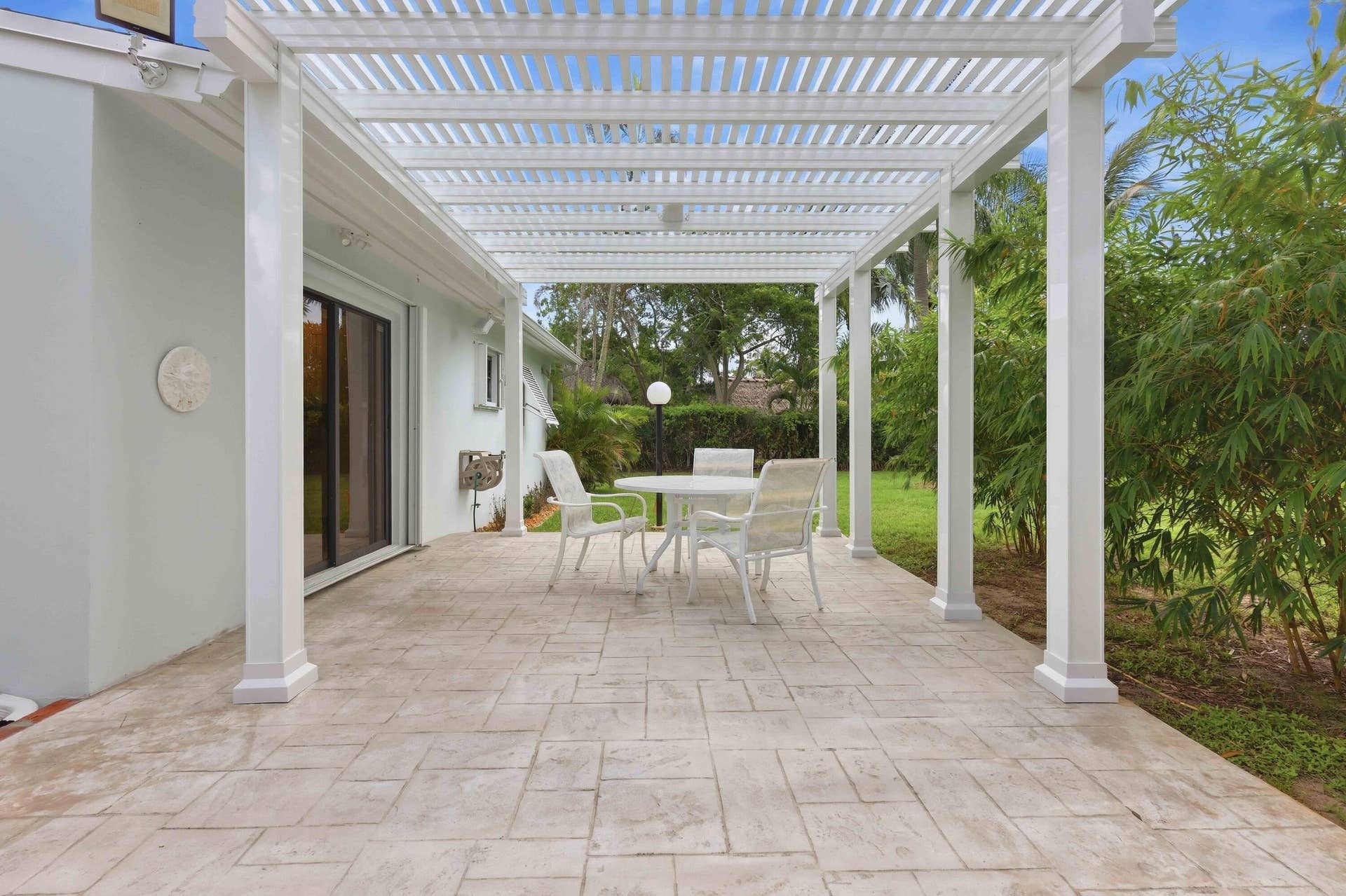 Expansive stamped concrete patio featuring a white pergola, offering an outdoor living area