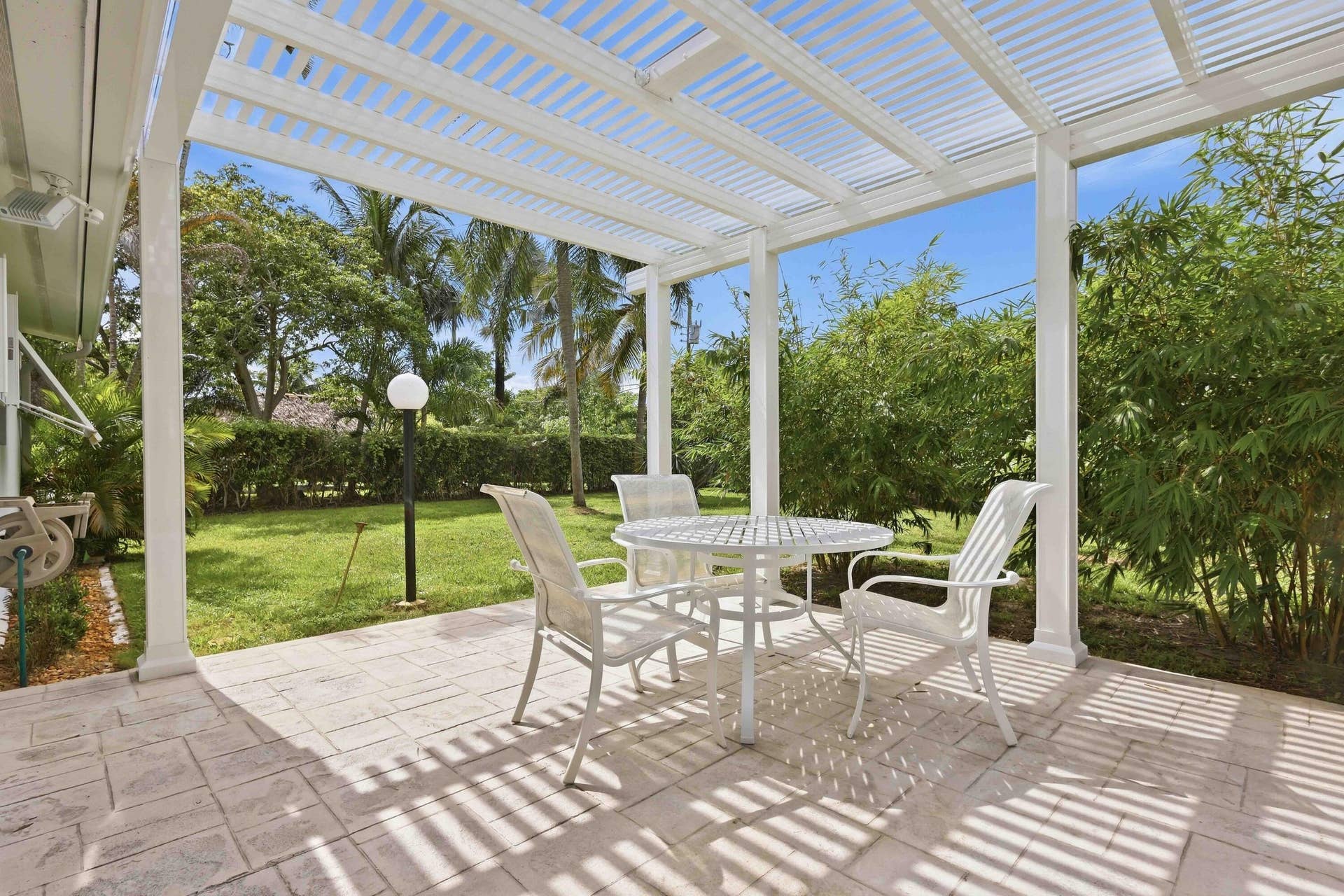 Covered patio with a slatted roof structure, featuring a stamped concrete surface