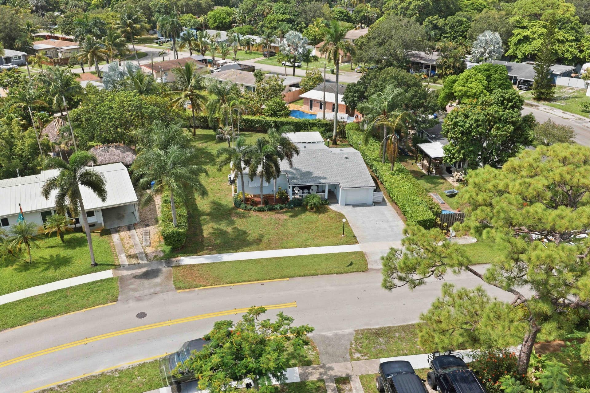 Single-story residence with an attached garage, paved driveway, and mature landscaping