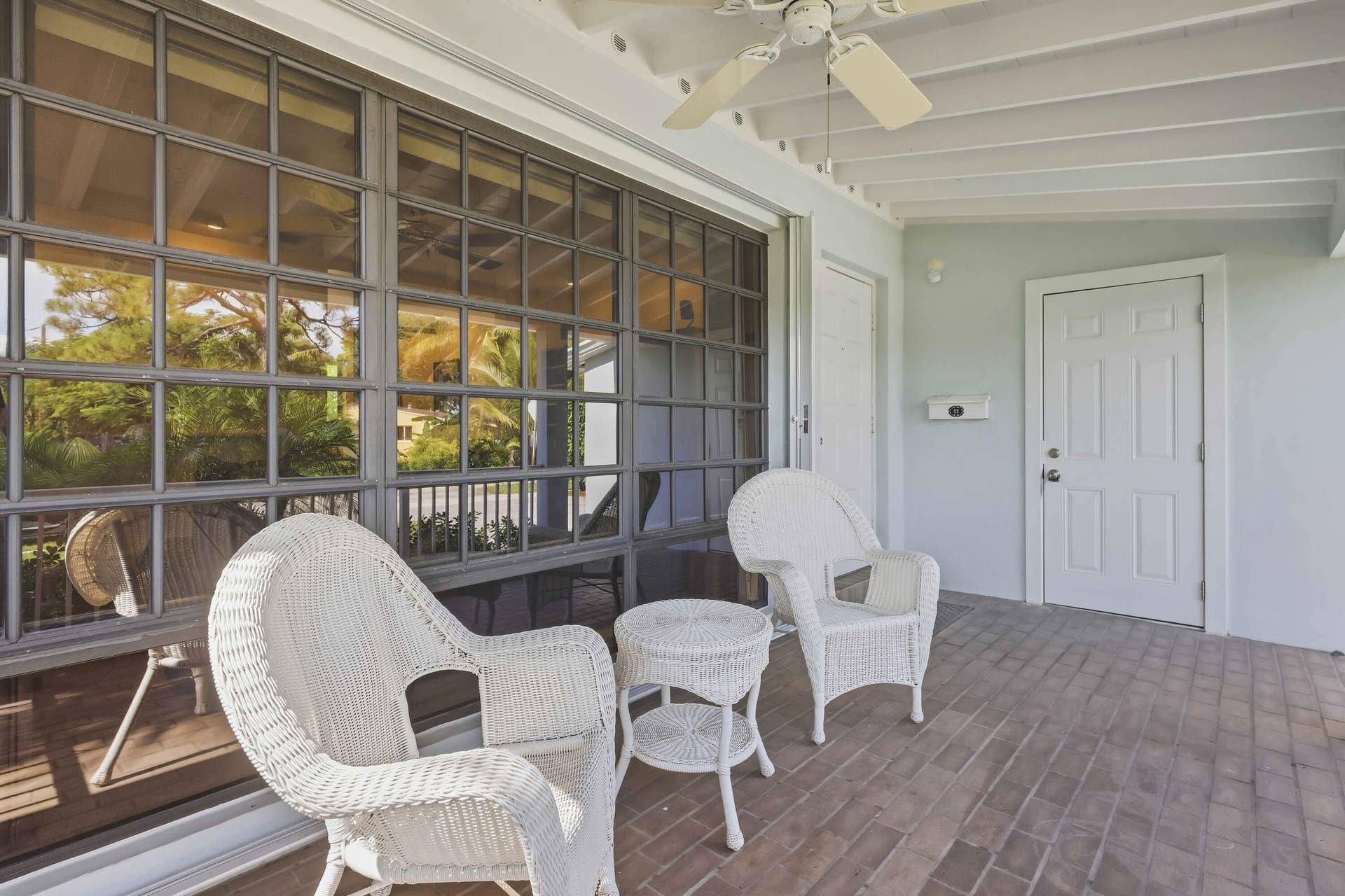 Covered patio with a brick-patterned floor, exposed beam ceiling, and a ceiling fan