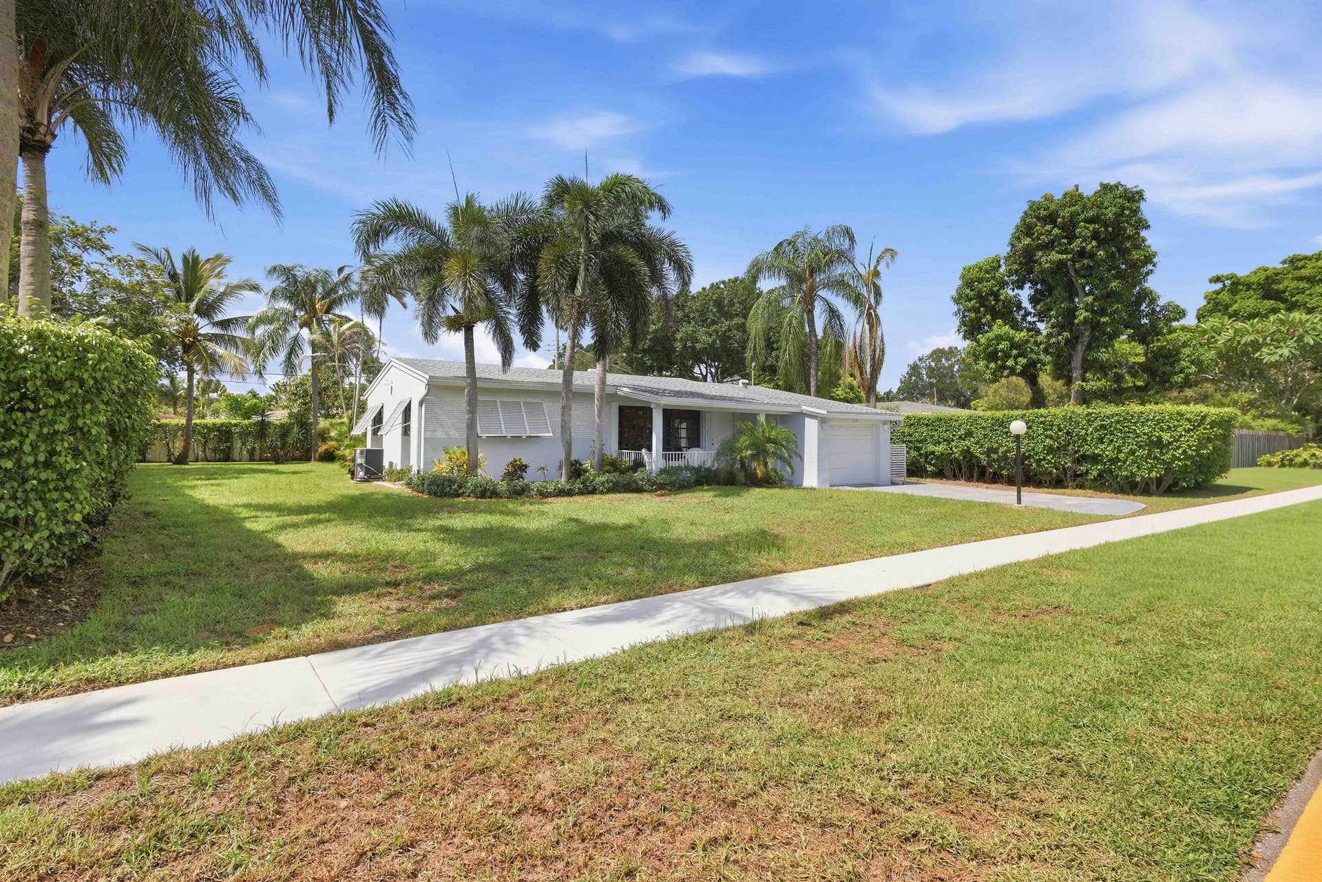 Single-story residence with a white exterior, attached garage, and mature palm trees