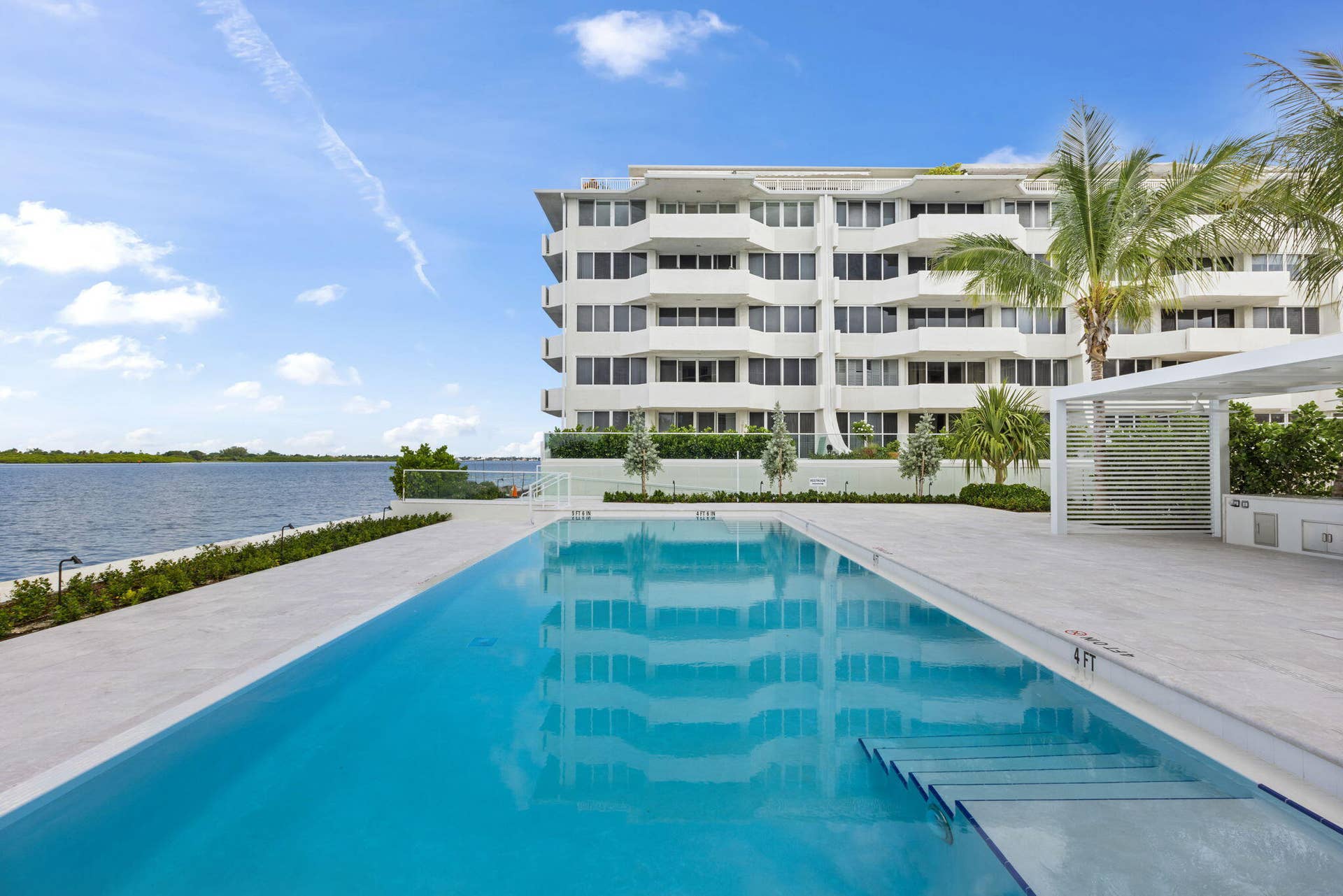 2773 S Ocean Boulevard, #517, Palm Beach, Palm Beach, FL 33480 Modern high-rise residential building with multiple balconies, expansive outdoor swimming pool with submerged steps, white hardscaping, and a contemporary pergola structure
