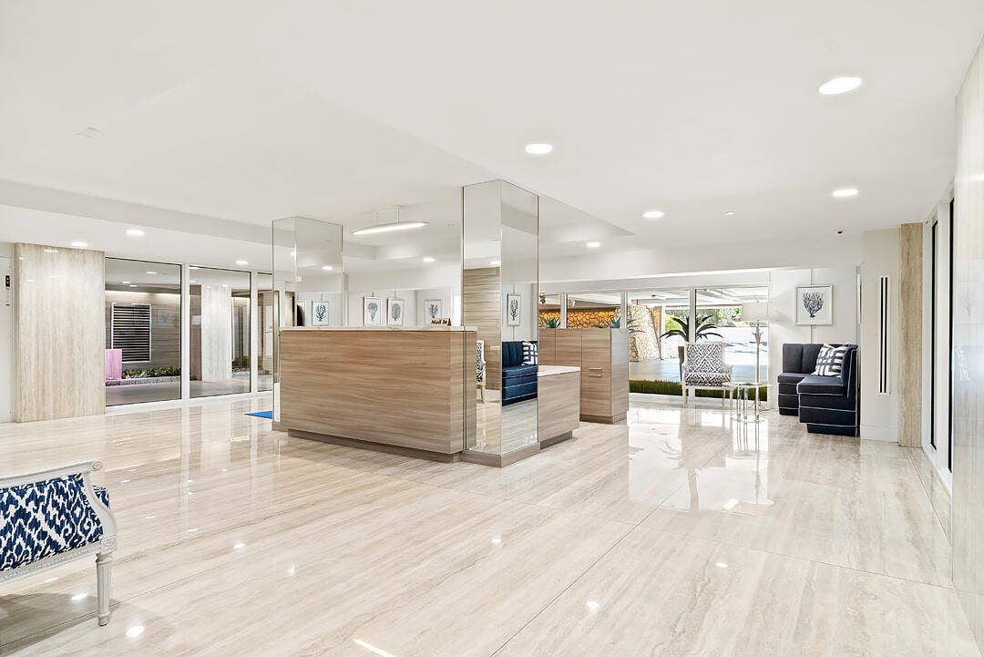 2773 S Ocean Boulevard, #517, Palm Beach, Palm Beach, FL 33480 Polished stone tile flooring, recessed ceiling lighting, wood-finish reception desk, mirrored columns, and expansive glass exterior
