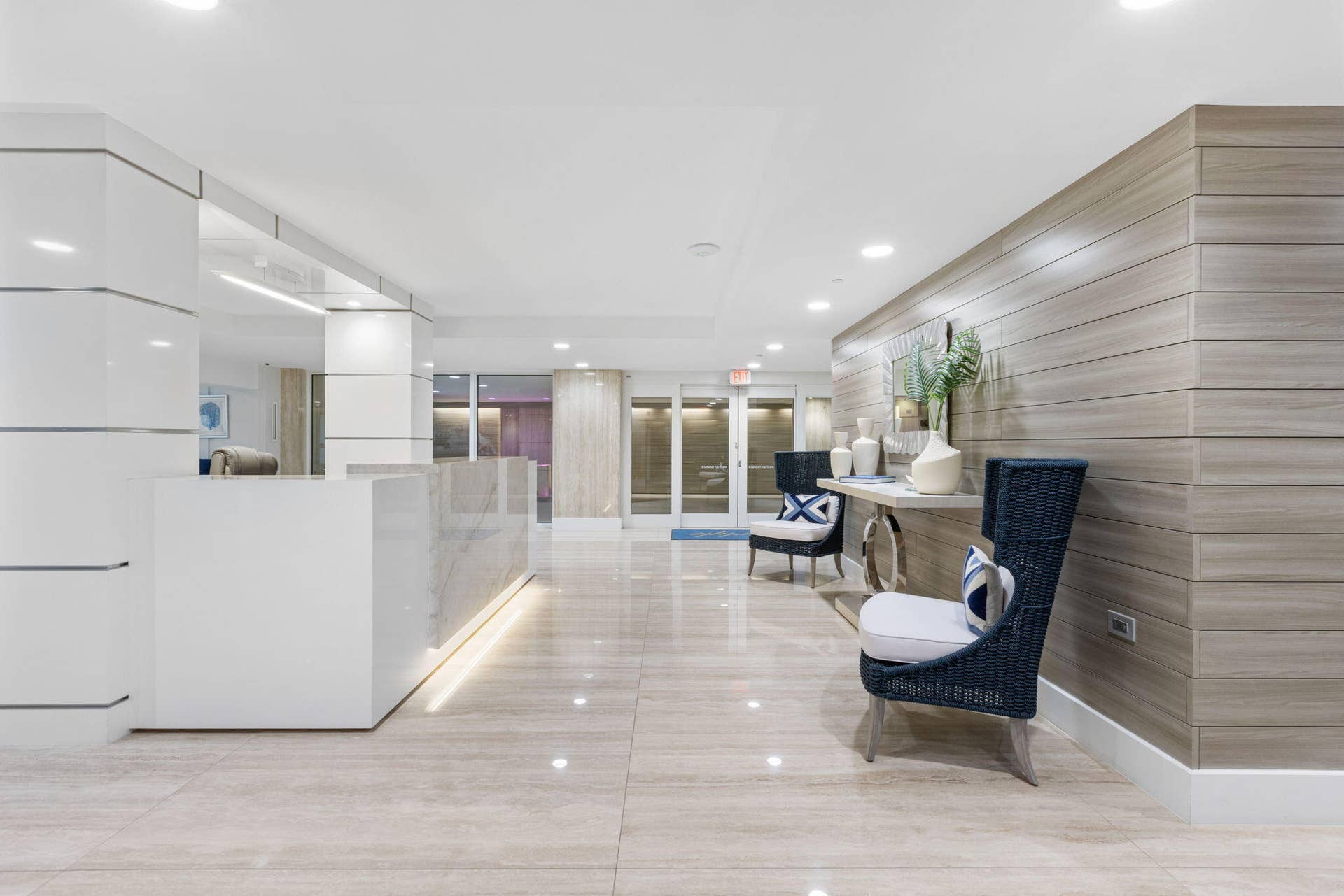2773 S Ocean Boulevard, #517, Palm Beach, Palm Beach, FL 33480 Polished stone flooring, wood-panel accent wall, recessed lighting, white reception desk with stone countertop, and contemporary seating