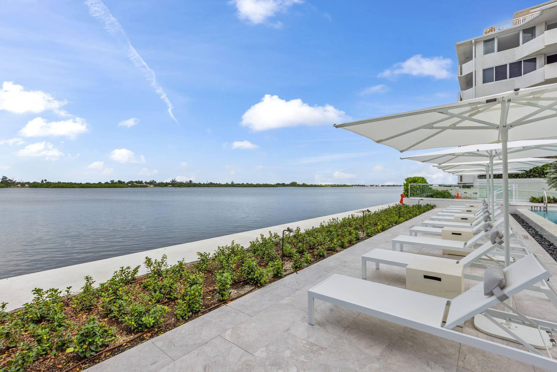 2773 S Ocean Boulevard, #517, Palm Beach, Palm Beach, FL 33480 Waterfront property featuring a paver patio with landscaping, lounge chairs, and shade umbrellas