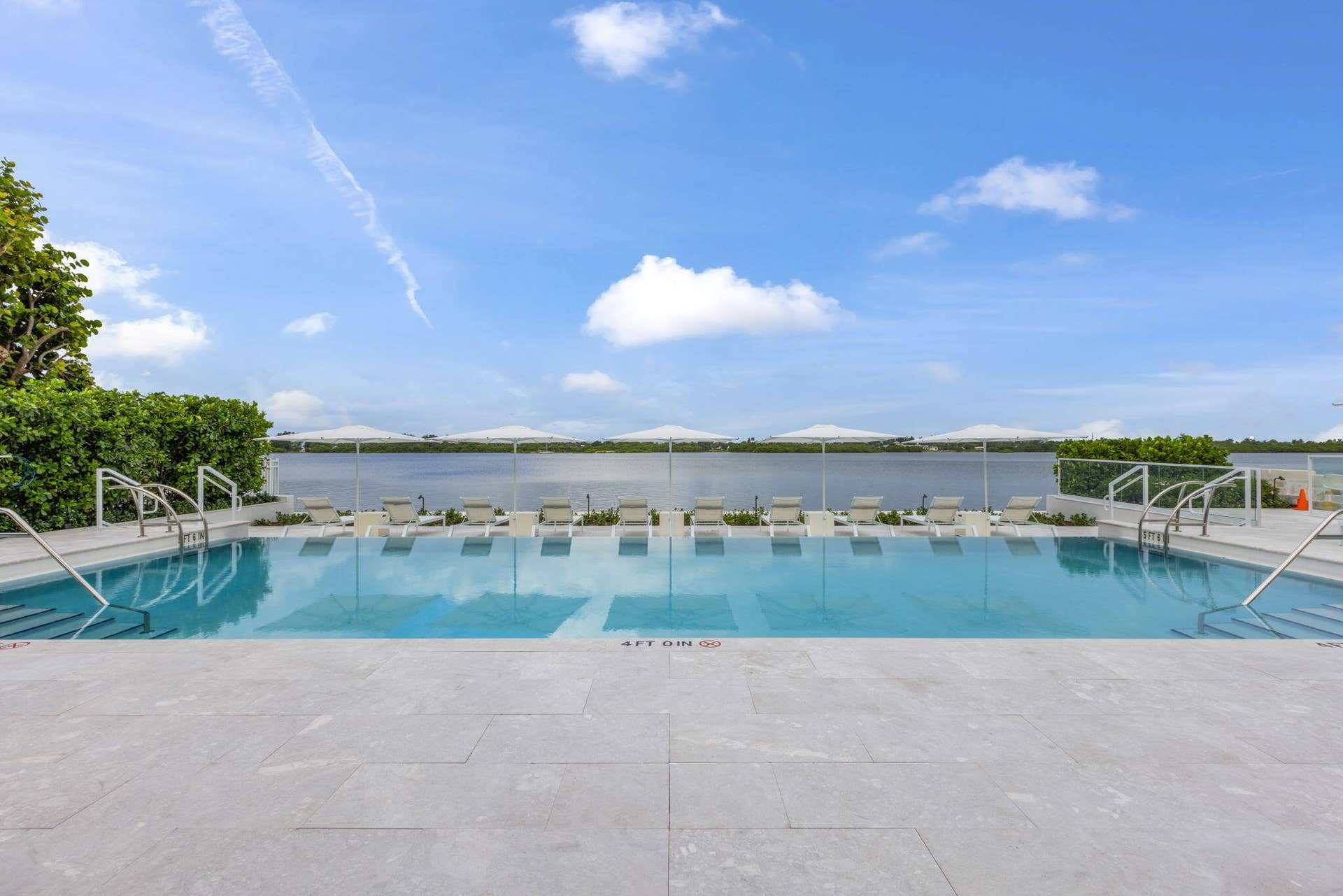 2773 S Ocean Boulevard, #517, Palm Beach, Palm Beach, FL 33480 Expansive outdoor pool with integrated steps, surrounded by a light-toned paved deck, and featuring a clear glass safety barrier