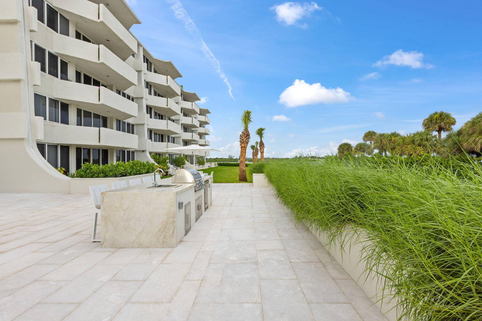 2773 S Ocean Boulevard, #517, Palm Beach, Palm Beach, FL 33480 Expansive outdoor patio with large format pavers, an integrated outdoor kitchen featuring a built-in grill and sink, and lush landscaping