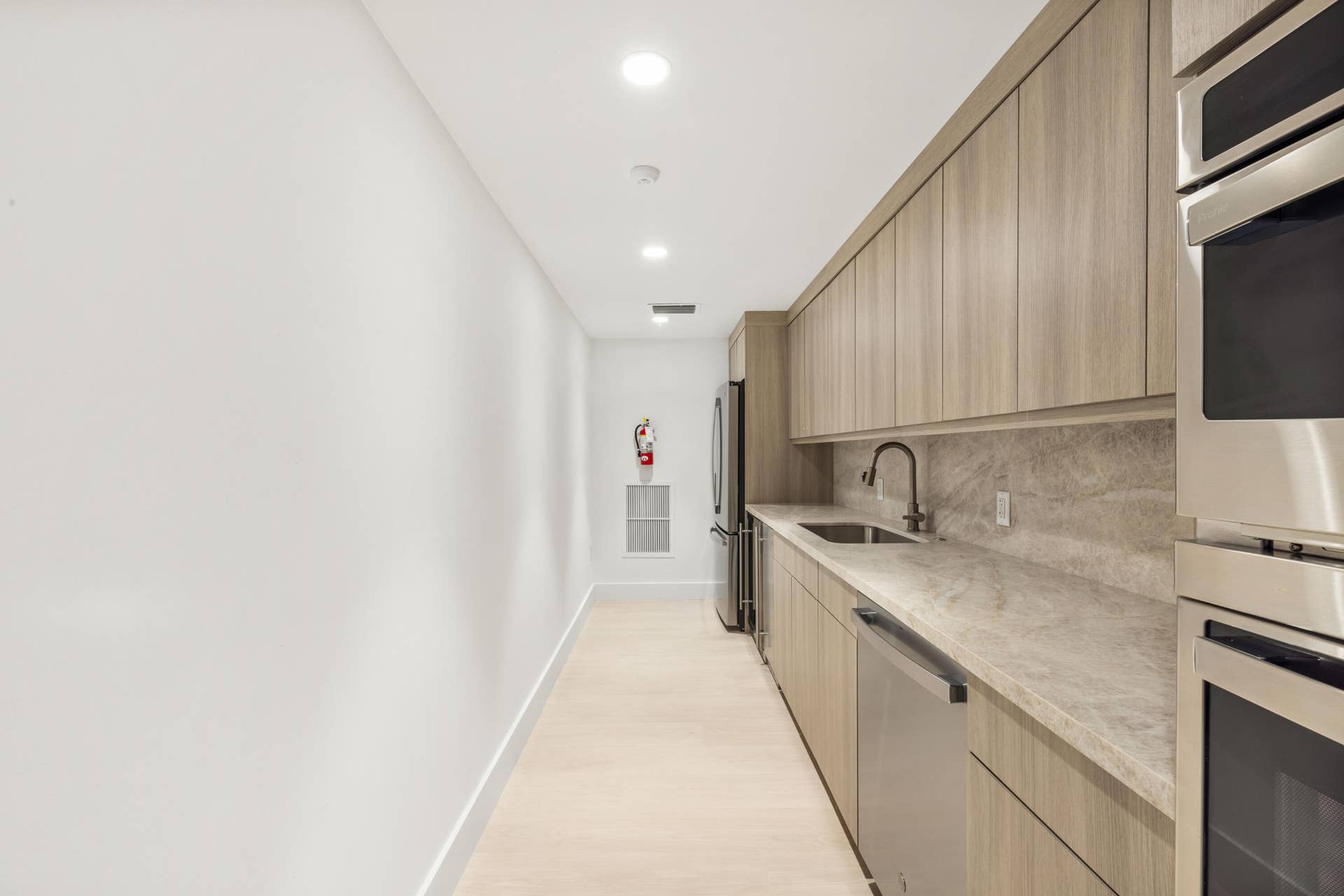 2773 S Ocean Boulevard, #517, Palm Beach, Palm Beach, FL 33480 Integrated kitchen area featuring wood-finish cabinetry, stainless steel appliances, a matte black faucet, and stone countertops with a matching backsplash