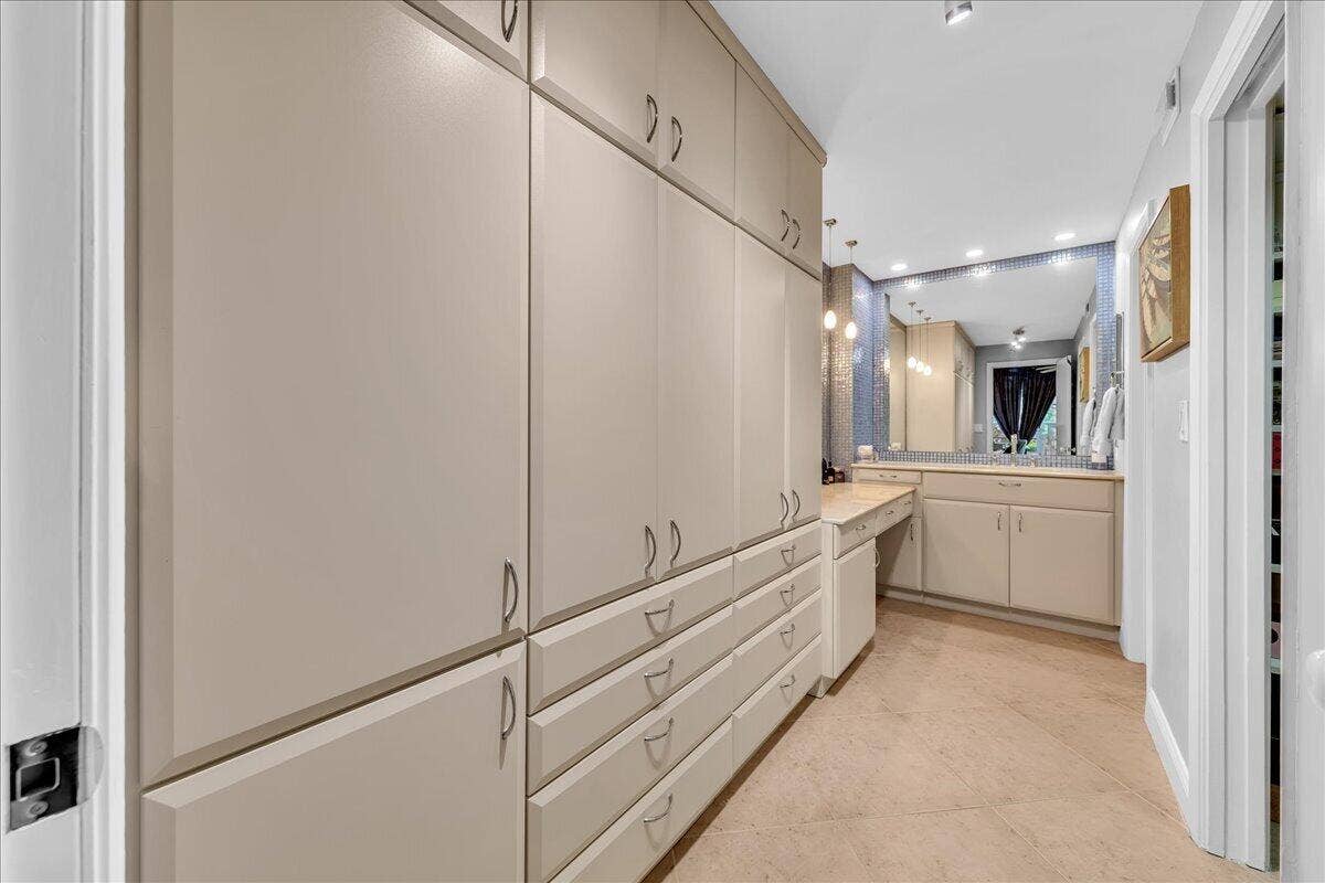3505 Oaks Way, #109, Pompano Beach, FL 33069 Extensive built-in cabinetry with ample storage, vanity with integrated countertop, large mirror, and recessed lighting