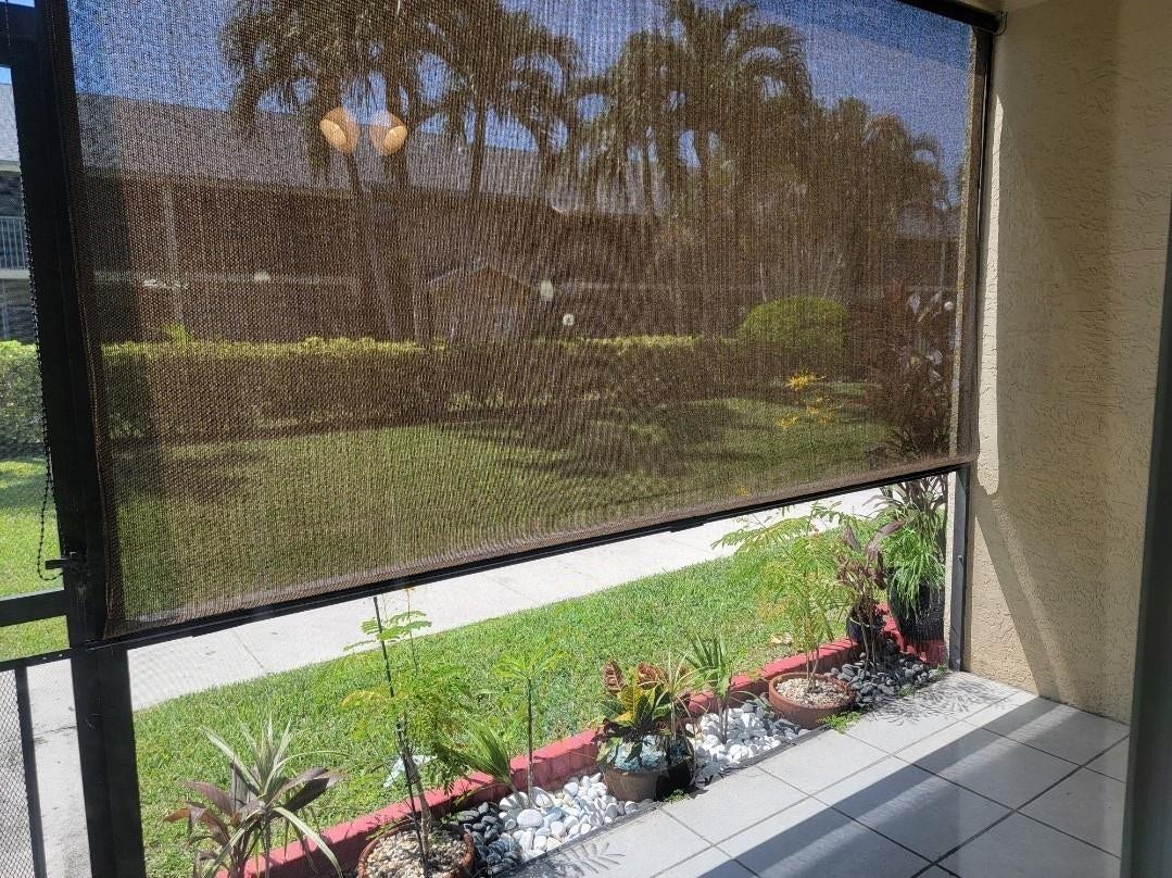 1001 SE 6TH Avenue, #127, Deerfield Beach, Deerfield Beach, FL 33441 Screened patio featuring a roller shade, tiled flooring, and a landscaped planter bed with white stones