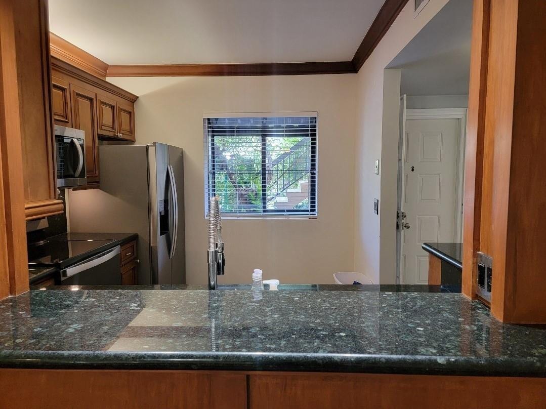 1001 SE 6TH Avenue, #127, Deerfield Beach, Deerfield Beach, FL 33441 Kitchen featuring wood cabinetry, dark speckled countertops, stainless steel appliances, and a window with horizontal blinds