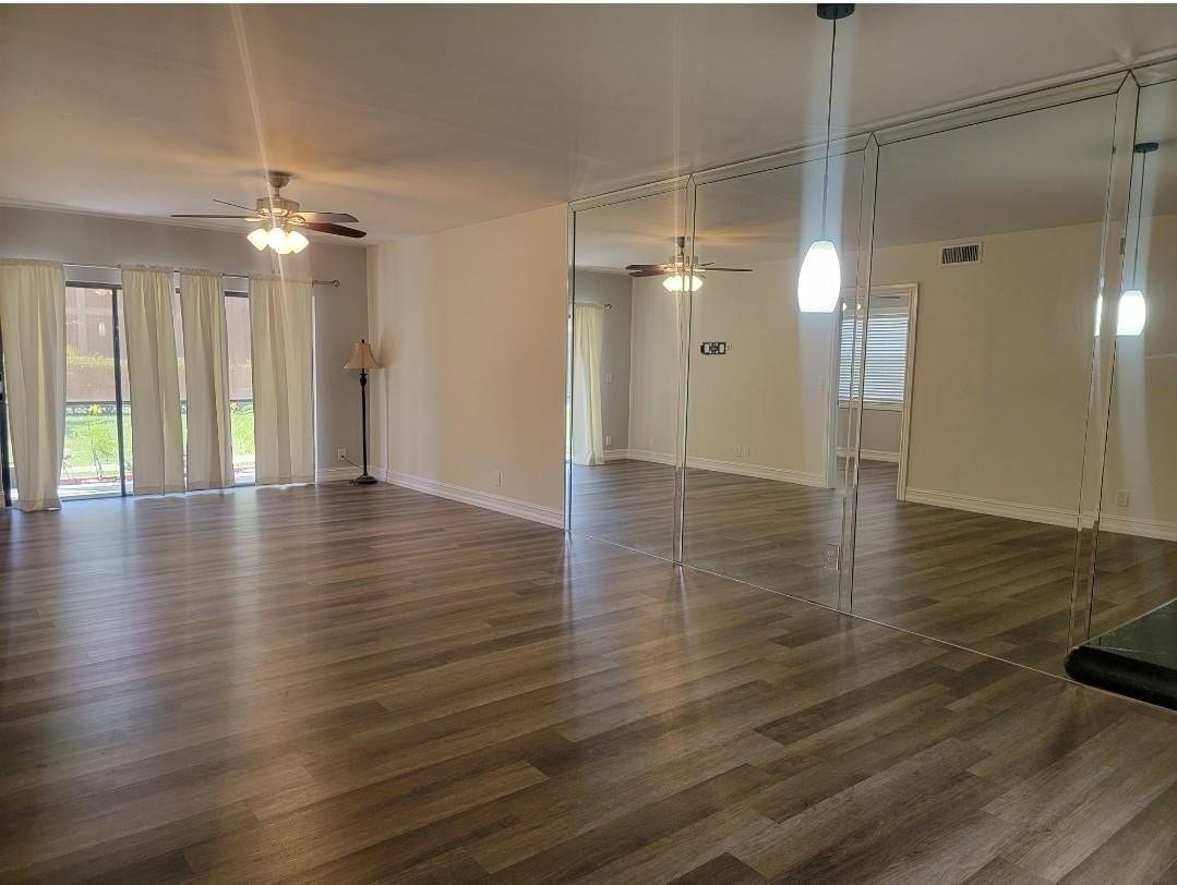 1001 SE 6TH Avenue, #127, Deerfield Beach, Deerfield Beach, FL 33441 Wood-finish flooring, ceiling fan, mirrored accent wall, and sliding glass doors