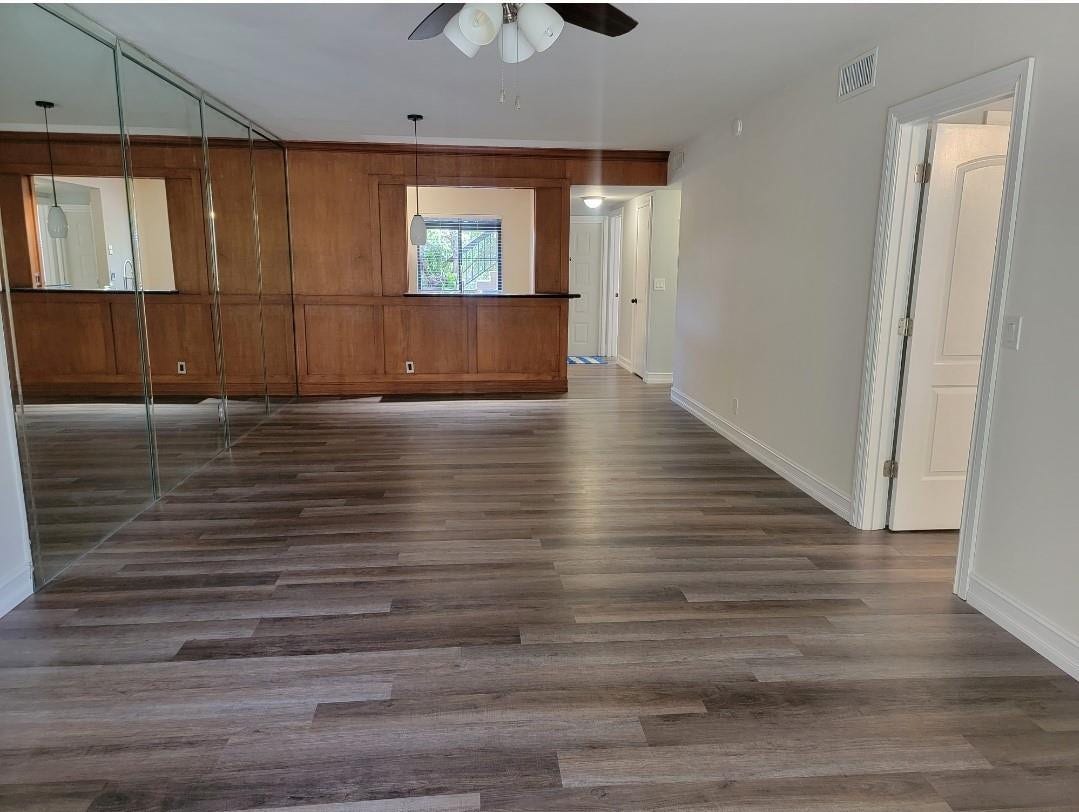 1001 SE 6TH Avenue, #127, Deerfield Beach, Deerfield Beach, FL 33441 Wood-finish flooring throughout, mirrored wall panels, wood paneled wall with pass-through openings, white trim, and a ceiling fan
