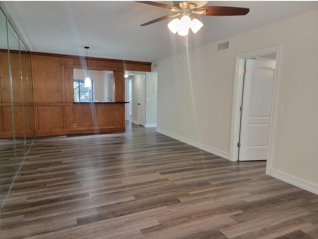 1001 SE 6TH Avenue, #127, Deerfield Beach, Deerfield Beach, FL 33441 Wood-finish flooring, wood paneling, mirrored wall, ceiling fan with integrated lighting, and white interior doors