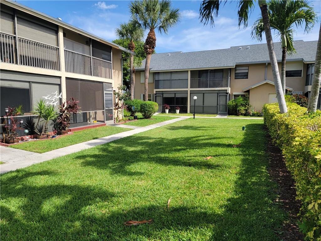 1001 SE 6TH Avenue, #127, Deerfield Beach, Deerfield Beach, FL 33441 Manicured lawn with mature palm trees, paved walkways, and screened lanais