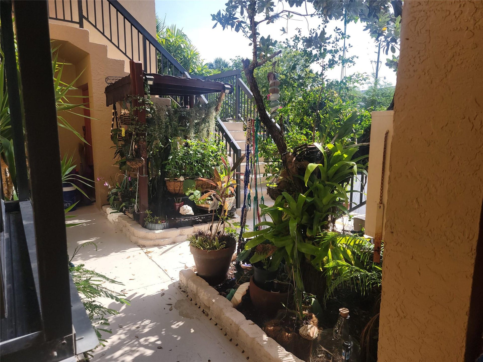 1001 SE 6TH Avenue, #127, Deerfield Beach, Deerfield Beach, FL 33441 Staircase with wrought iron railing, stucco exterior, and planted garden beds