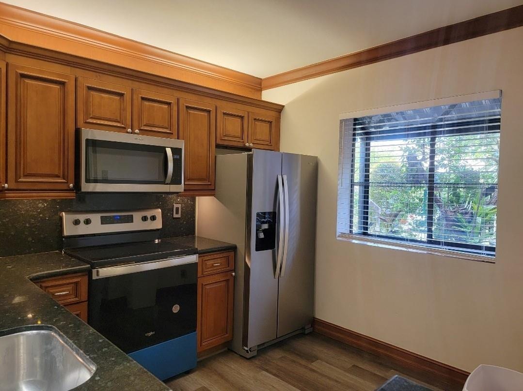 1001 SE 6TH Avenue, #127, Deerfield Beach, Deerfield Beach, FL 33441 Wood-finish cabinetry with crown molding, stainless steel appliances, dark stone countertops, stainless steel sink, and wood-finish flooring