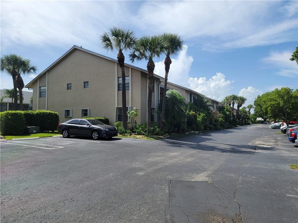 1001 SE 6TH Avenue, #127, Deerfield Beach, Deerfield Beach, FL 33441 Stucco exterior with multiple windows, surrounded by mature palm trees and manicured hedges, with a paved parking area