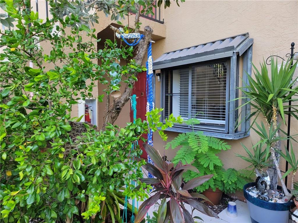 1001 SE 6TH Avenue, #127, Deerfield Beach, Deerfield Beach, FL 33441 Stucco exterior with an angled window awning, framed by lush foliage and mature plantings