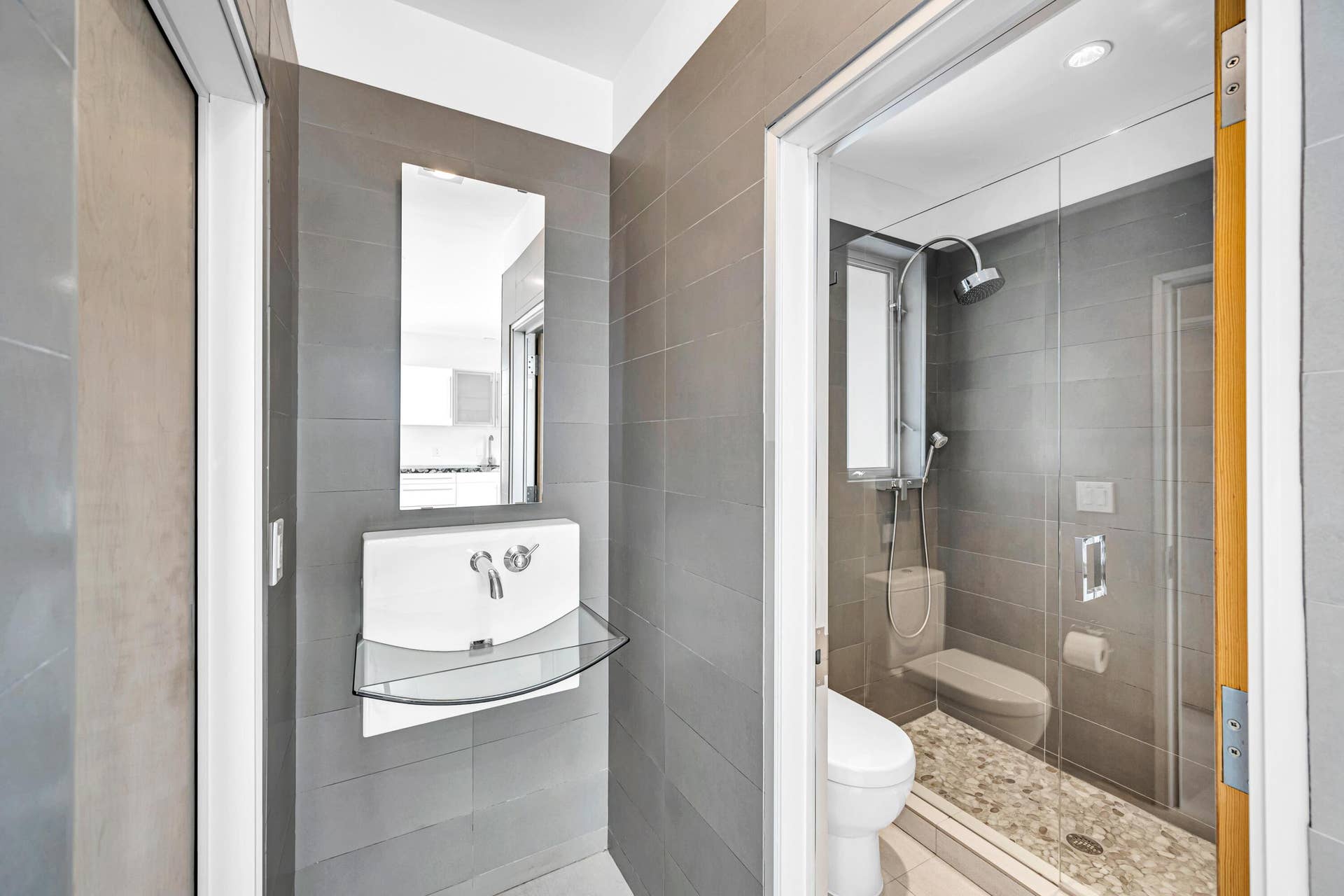 510 SW 18th Avenue, Fort Lauderdale, FL 33312 Modern bathroom featuring gray tiled walls, a wall-mounted sink with a glass shelf, and a mirror